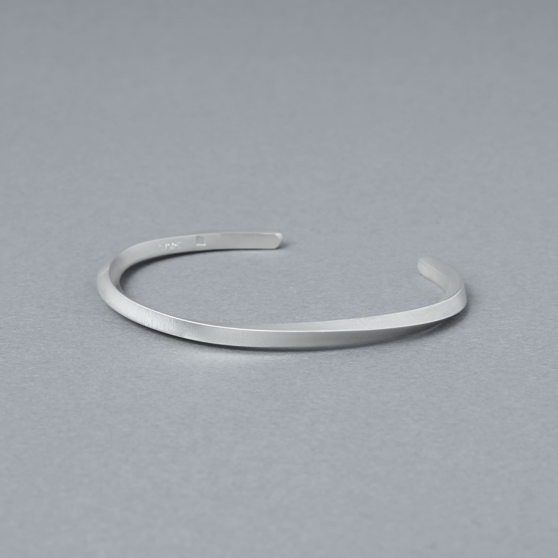 内側の刻印が見える角度で撮影したマットシルバーのバングル。程よい厚みと均一なラインを確認できる商品カット。