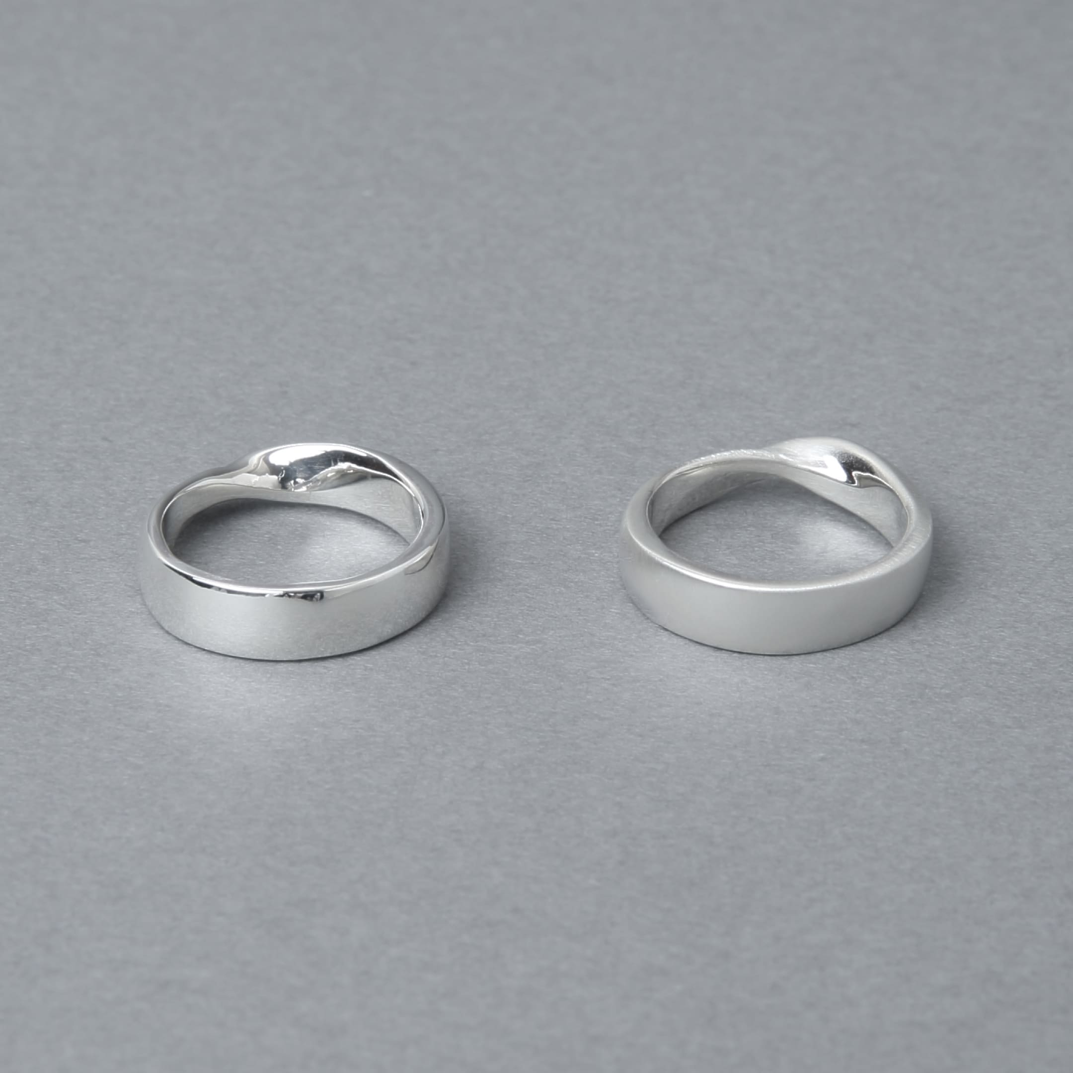 2つのシルバー925製リングが並べられており、左は鏡面仕上げで光沢のあるデザイン、右はマット仕上げで落ち着いた質感が特徴的。背景はグレーでシンプルな印象。