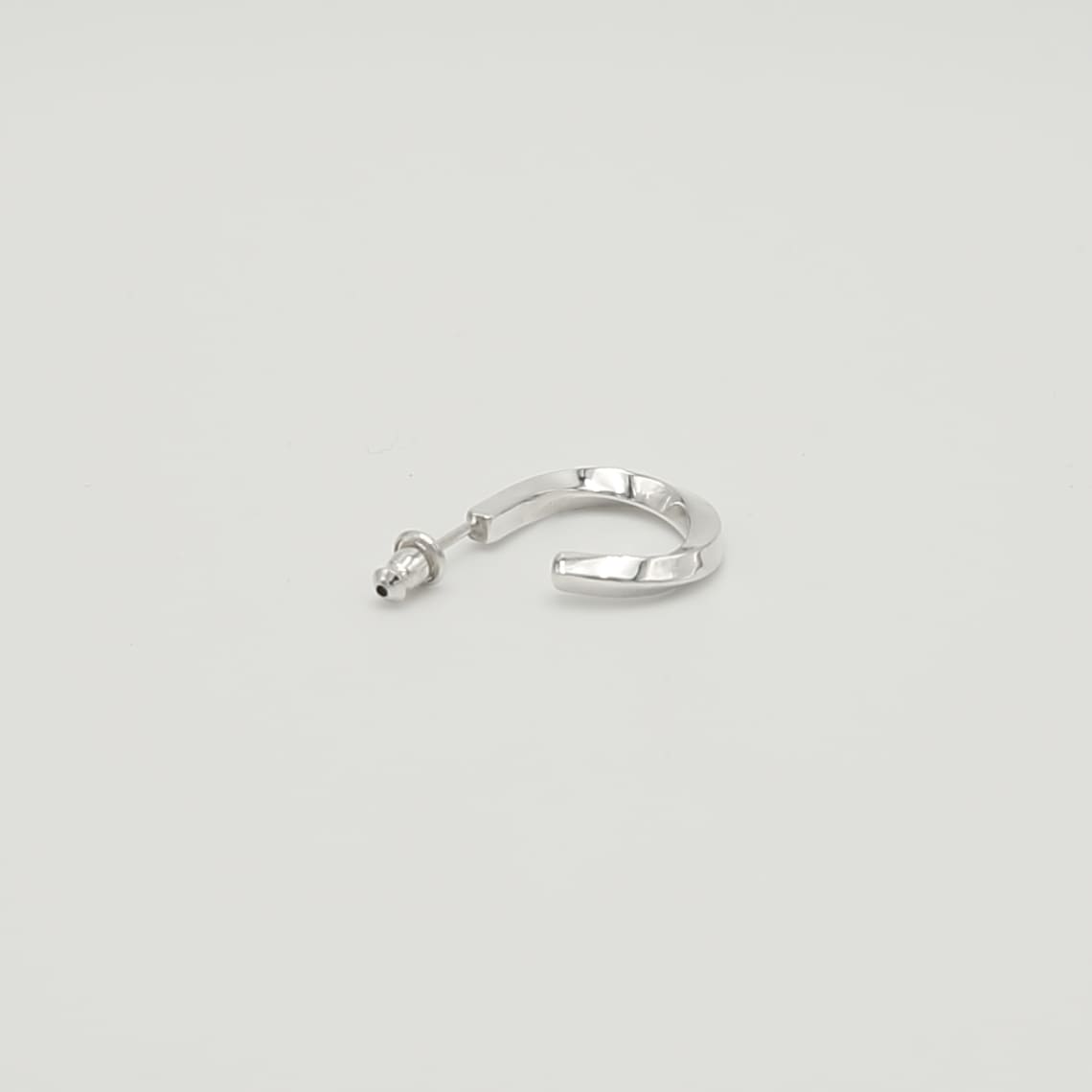 捻りのあるデザインが施されたシルバー925製の片耳用フープピアス。スタッドポスト仕様で、高品質な銀の質感が伝わる高精細な物撮り画像。