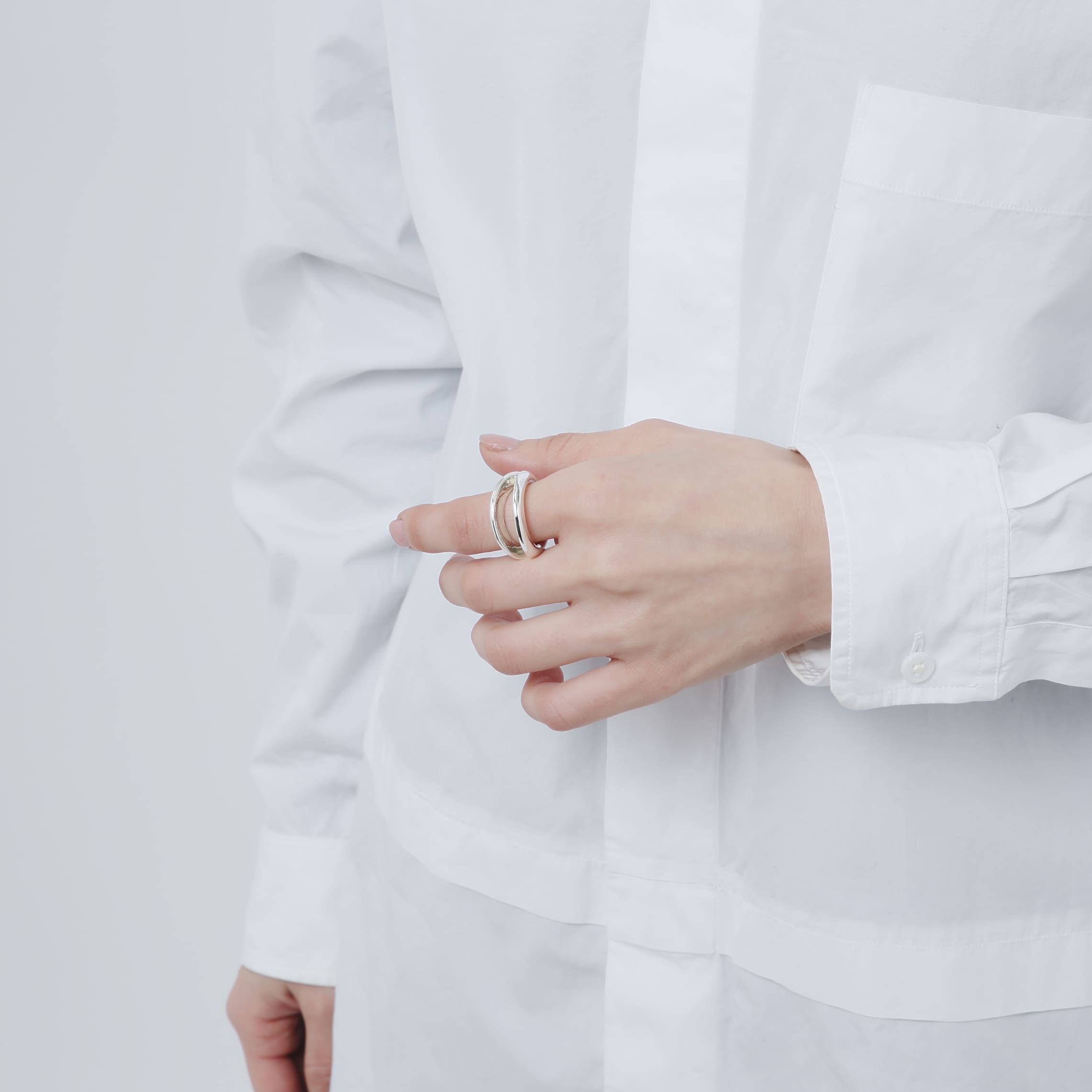 白シャツを着用したモデルが、人差し指にボリューム感のあるシルバー925製のリングをはめている正面カット。