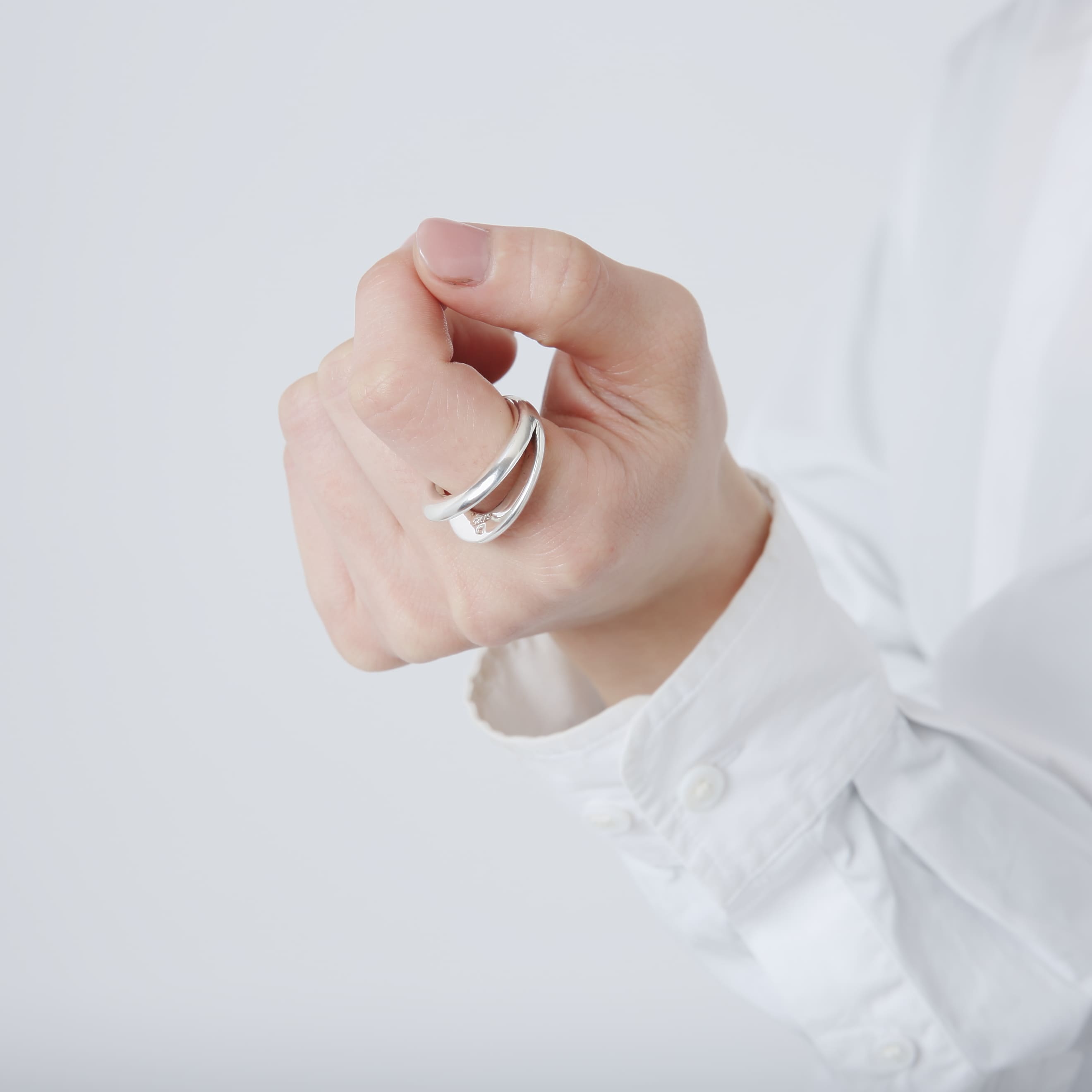 軽く拳を握ったポーズでのクローズアップ。シルバー925の質感と、内側に刻印が見えるリングのディテール。