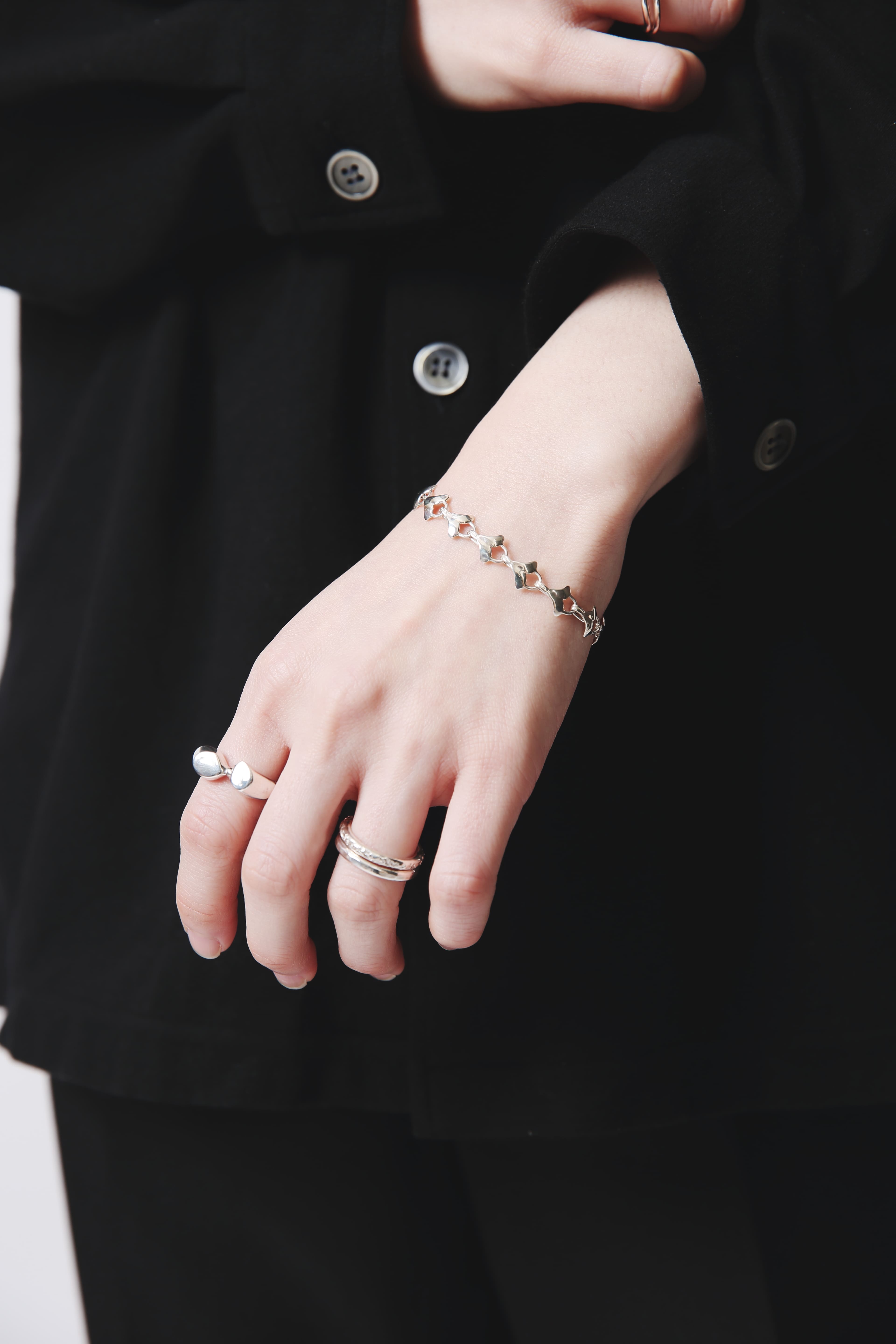 シンプルな黒のシャツと合わせたコーディネートの中に、イチョウの葉の造形が美しいシルバーブレスレットがさりげなく映える。