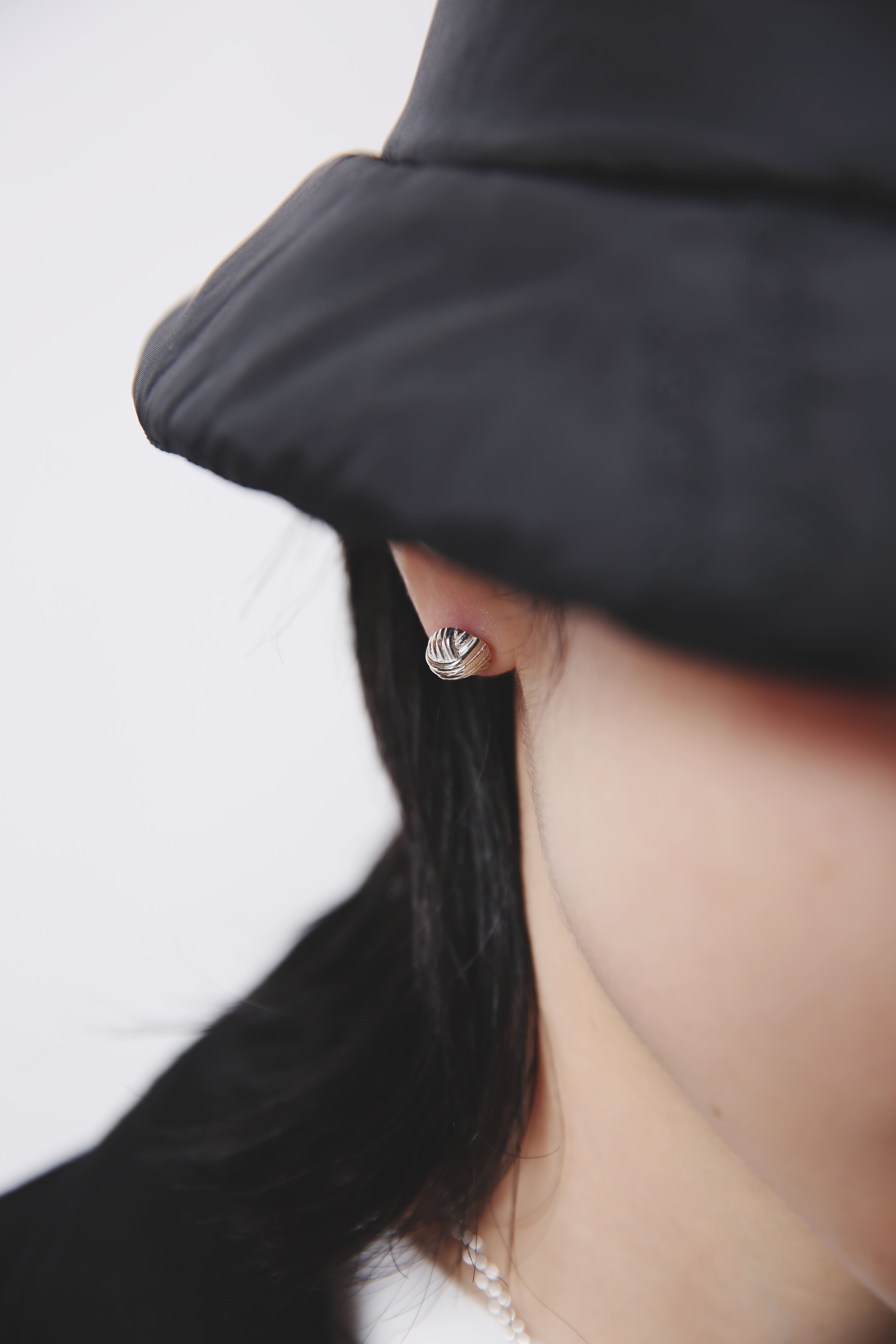 横顔に寄り添うシルバー925ピアスのアップ。重厚感のある輝きが、黒のウェアと対比して都会的な印象を与えます。