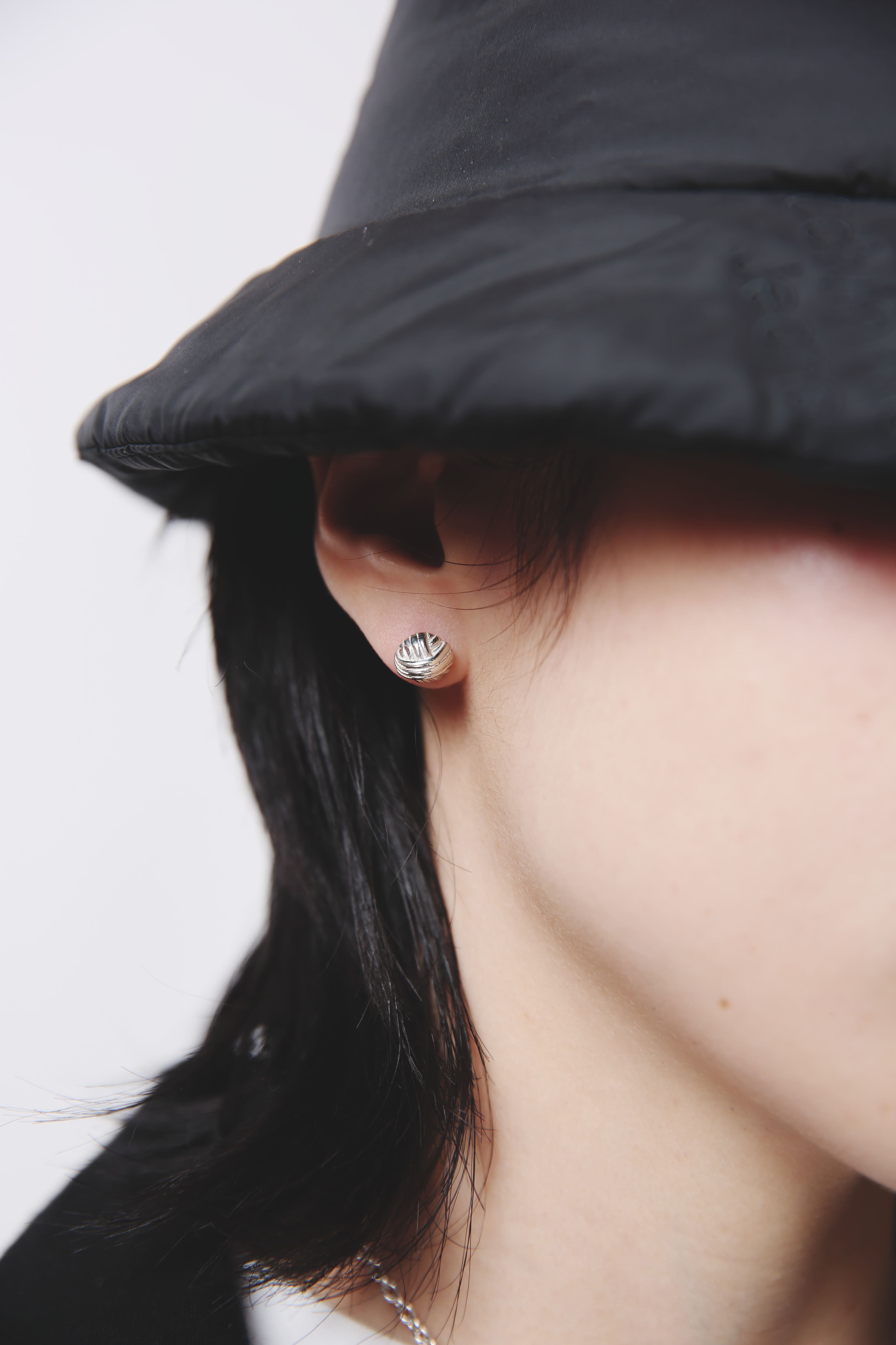 耳元にフォーカスしたクローズアップ。複雑に光を反射するシルバー925の質感と、耳たぶに収まる絶妙なサイズ感。