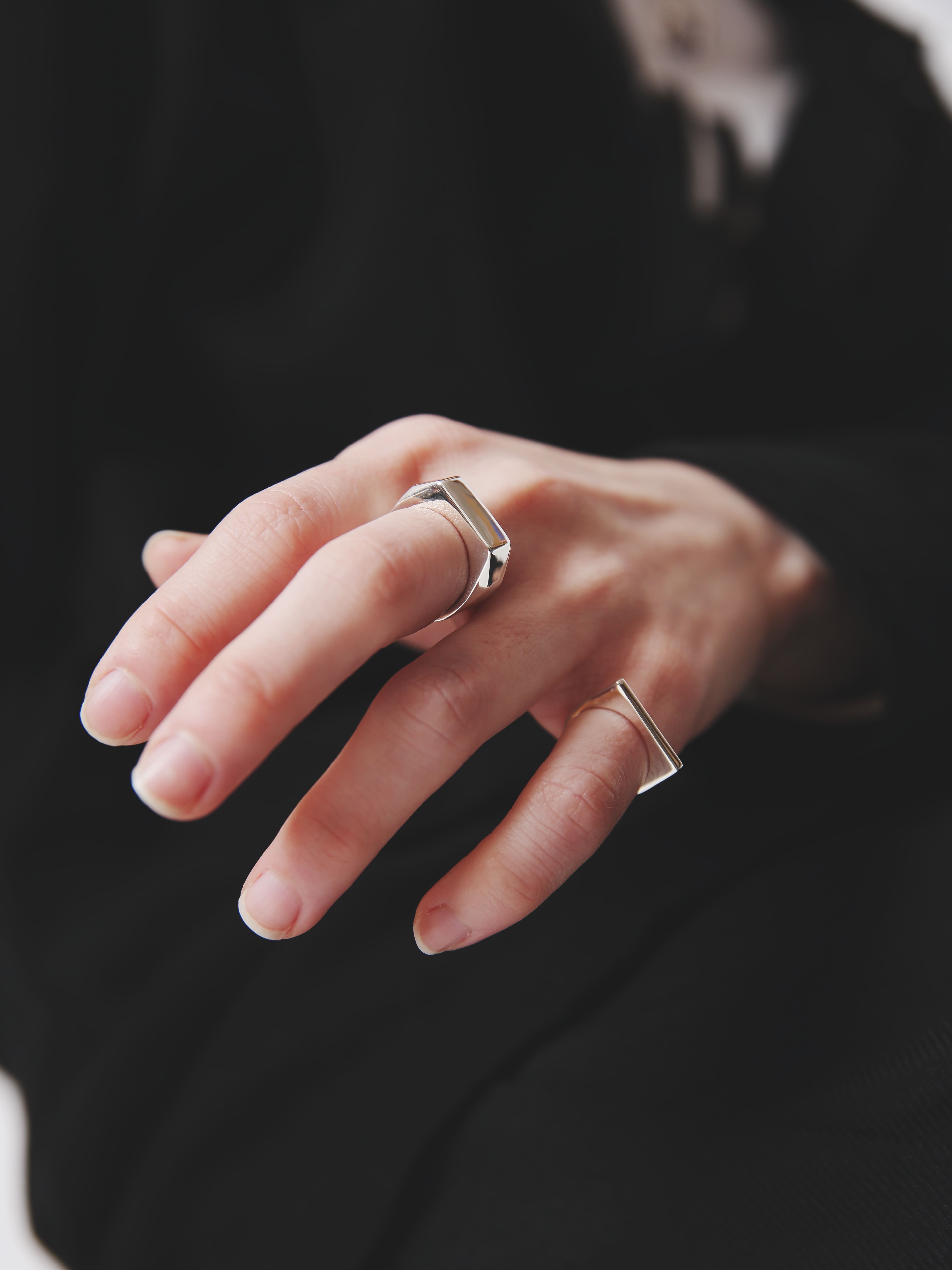 角度のあるフォルムが特徴的なシルバー925リングを中指に着用した手元のクローズアップ。ブラックコーデと好相性のミニマルデザイン。