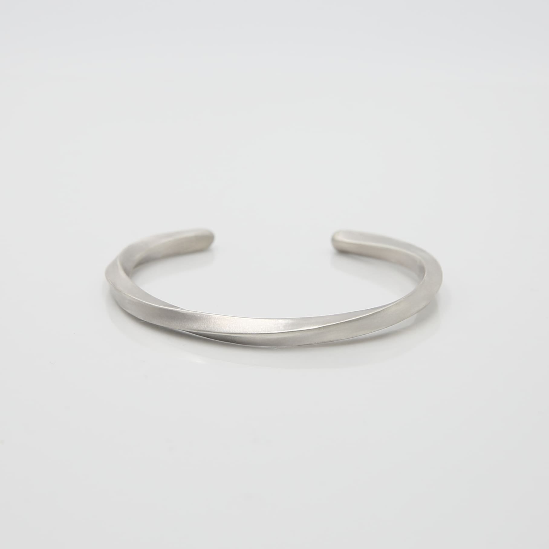 シルバー925製のシンプルなバングル。流れるような曲線が特徴のデザインで、マットな質感が落ち着いた印象を与える。