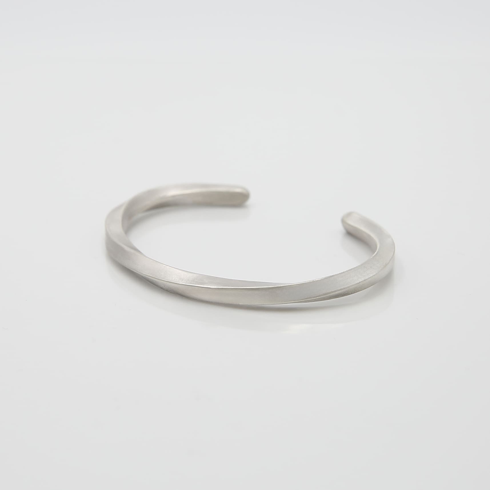 シルバー925製のシンプルなバングル。流れるような曲線が特徴のデザインで、マットな質感が落ち着いた印象を与える。