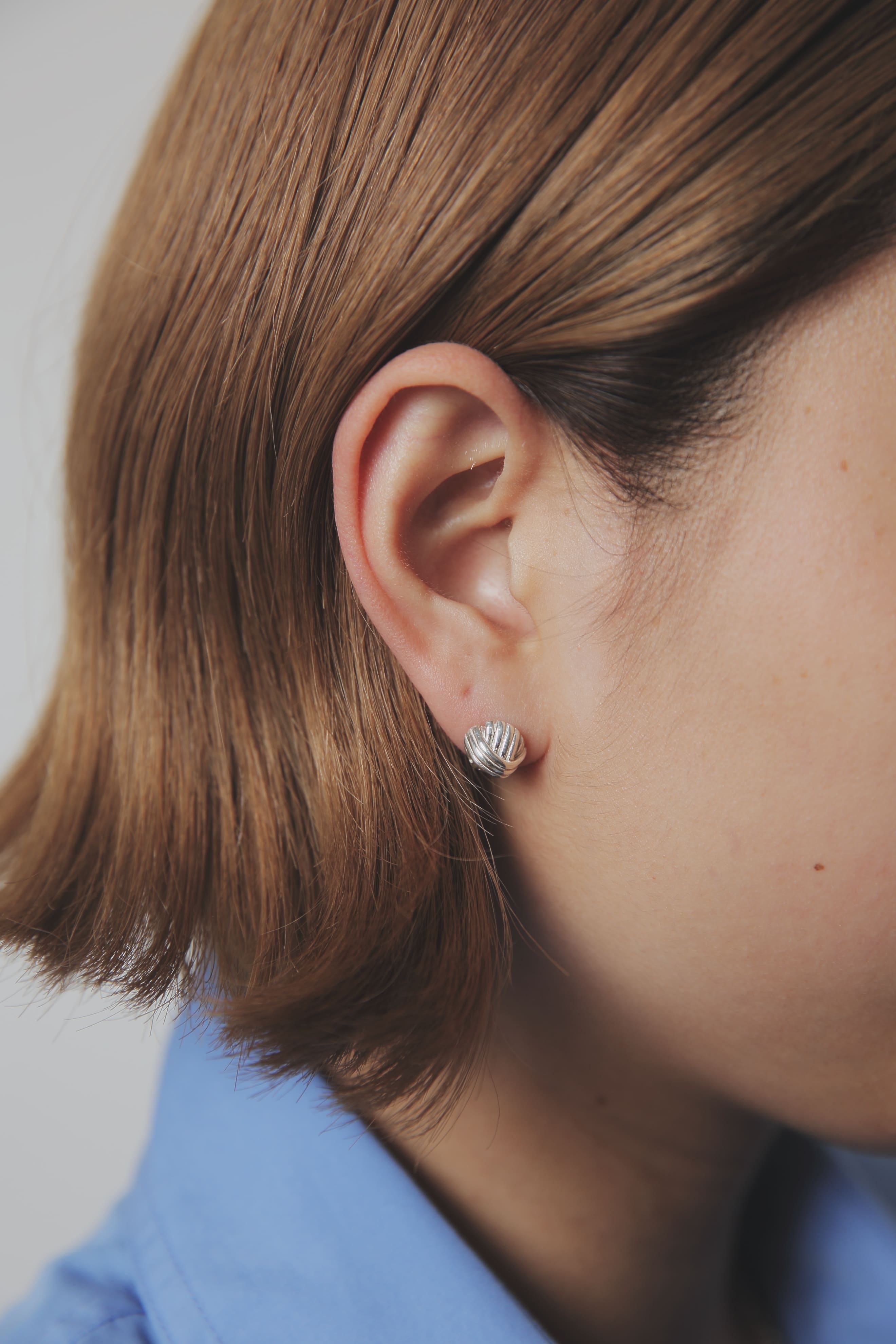 シンプルなシャツスタイルに映えるシルバー925ピアス。オンオフ問わず使いやすい、上品で立体的なデザイン。