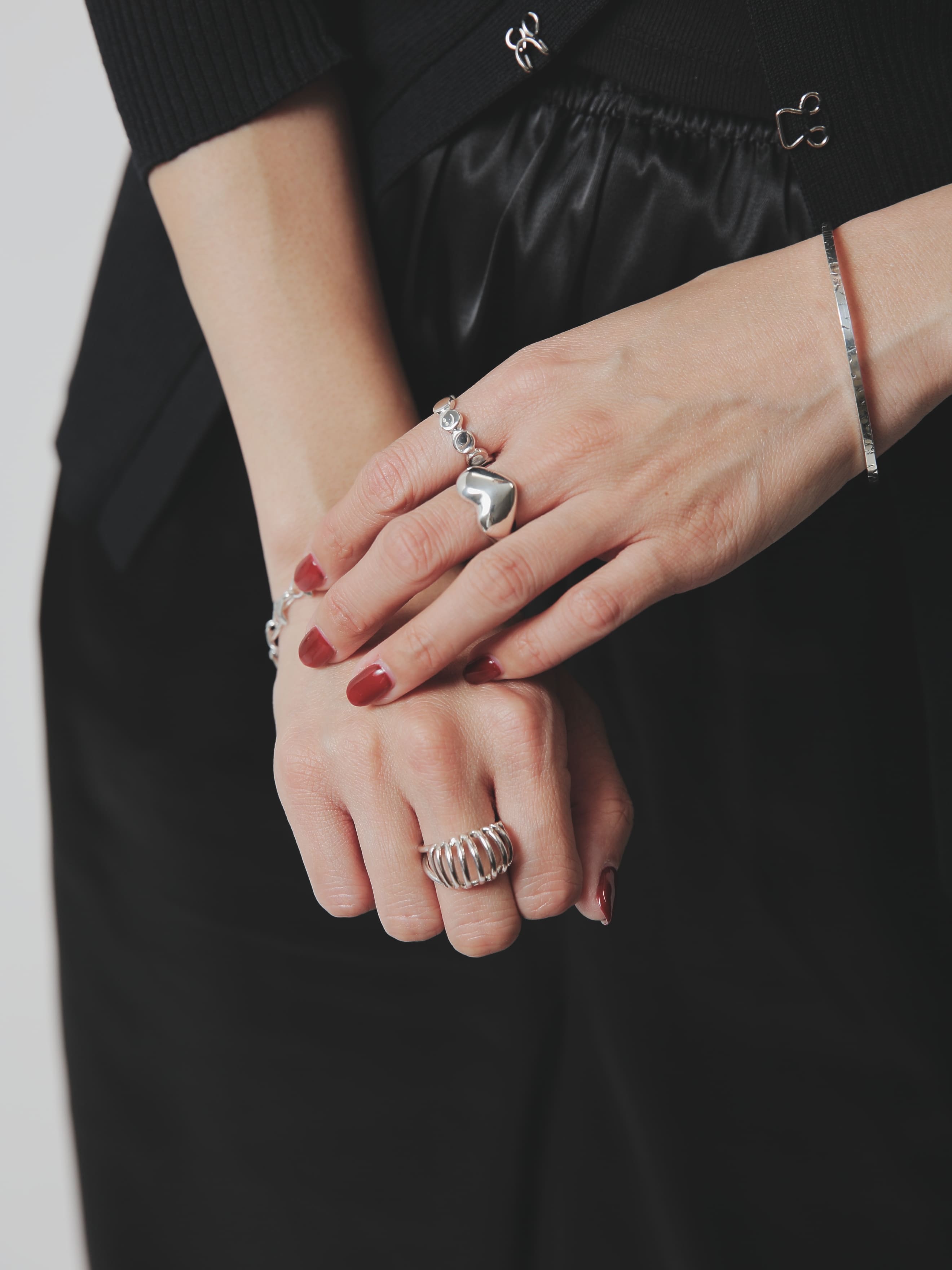 シルバー925製の存在感あるリングとバングルを複数重ね付けした手元コーディネート。赤系ネイルとブラックスタイルがアクセサリーを引き立てる。