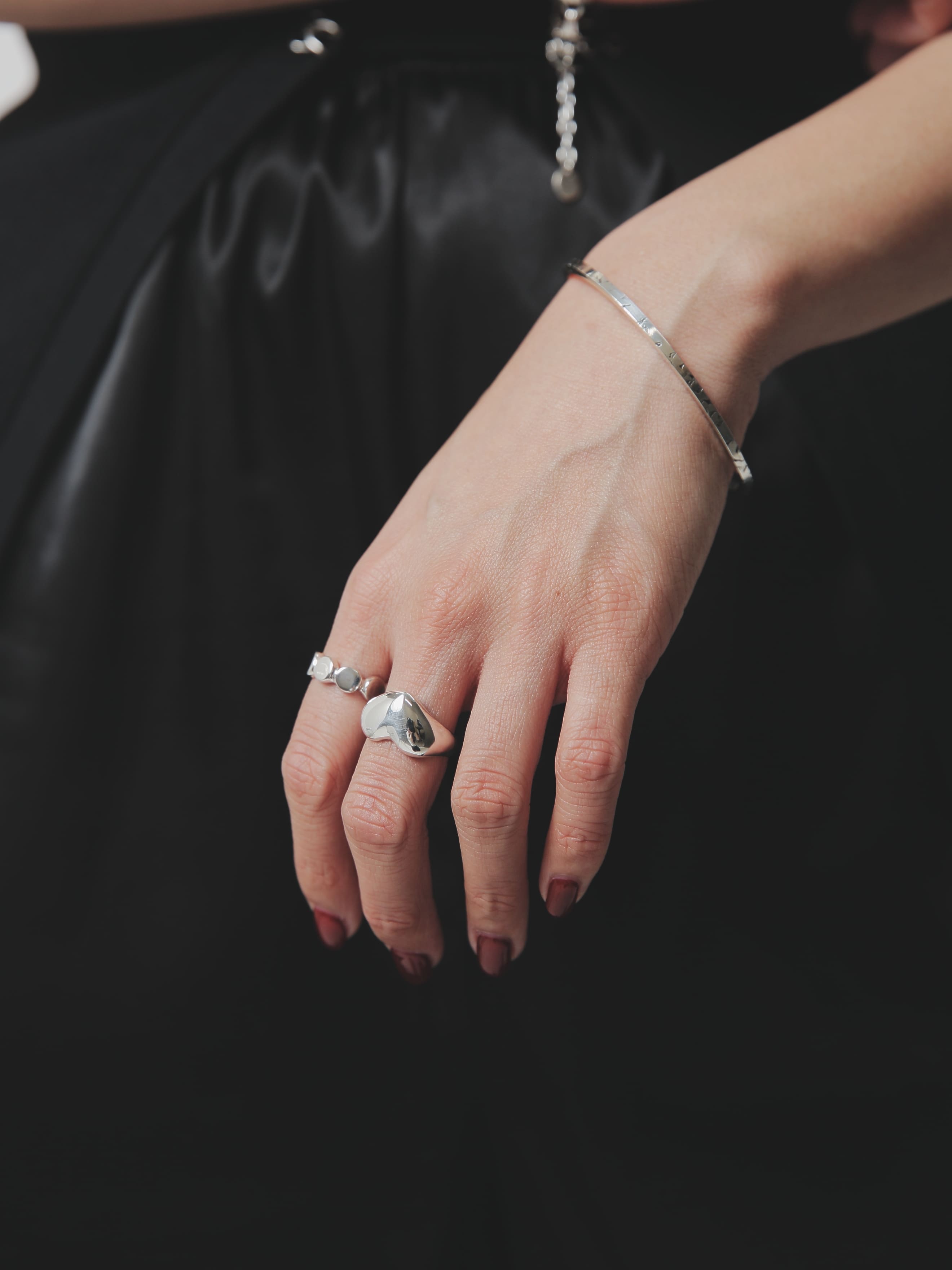 シルバー925特有の柔らかな光沢を放つハートリングと、ドットを繋げたようなリングを中指と薬指に。動きのある手のポーズが、シルバーの立体感と滑らかな質感を強調しています。