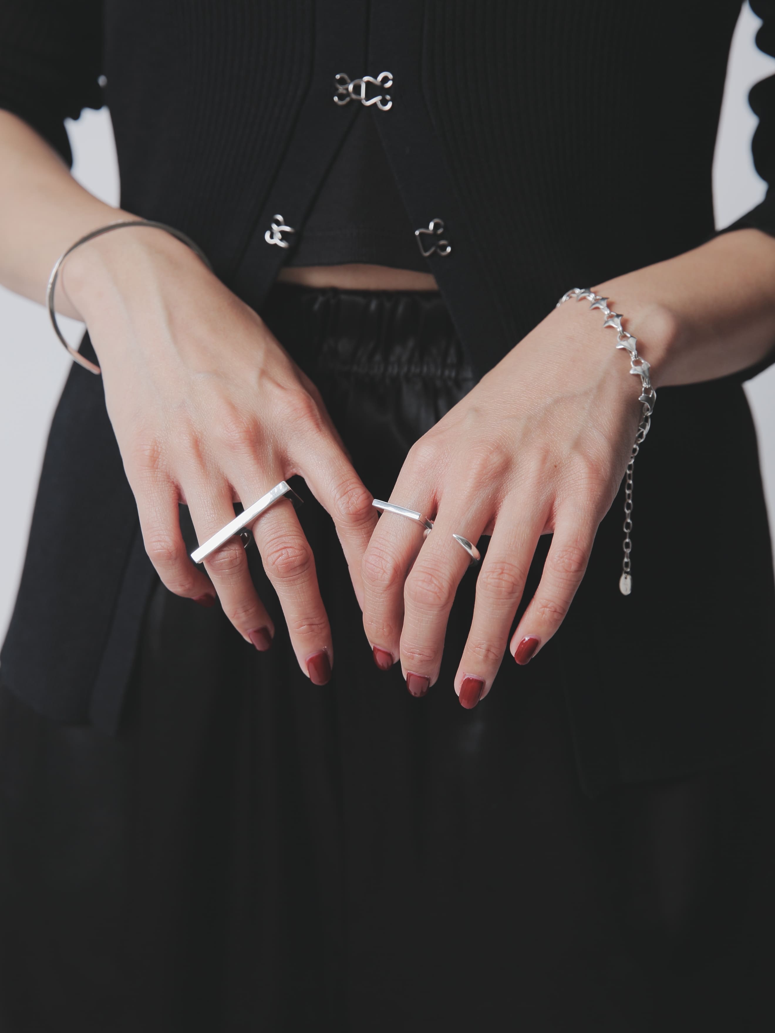 シルバー925製のボリューム感あるリングやバングルを重ね付けしたコーディネート。黒のトップスと赤系ネイルが手元のアクセサリーを際立たせるスタイリング。