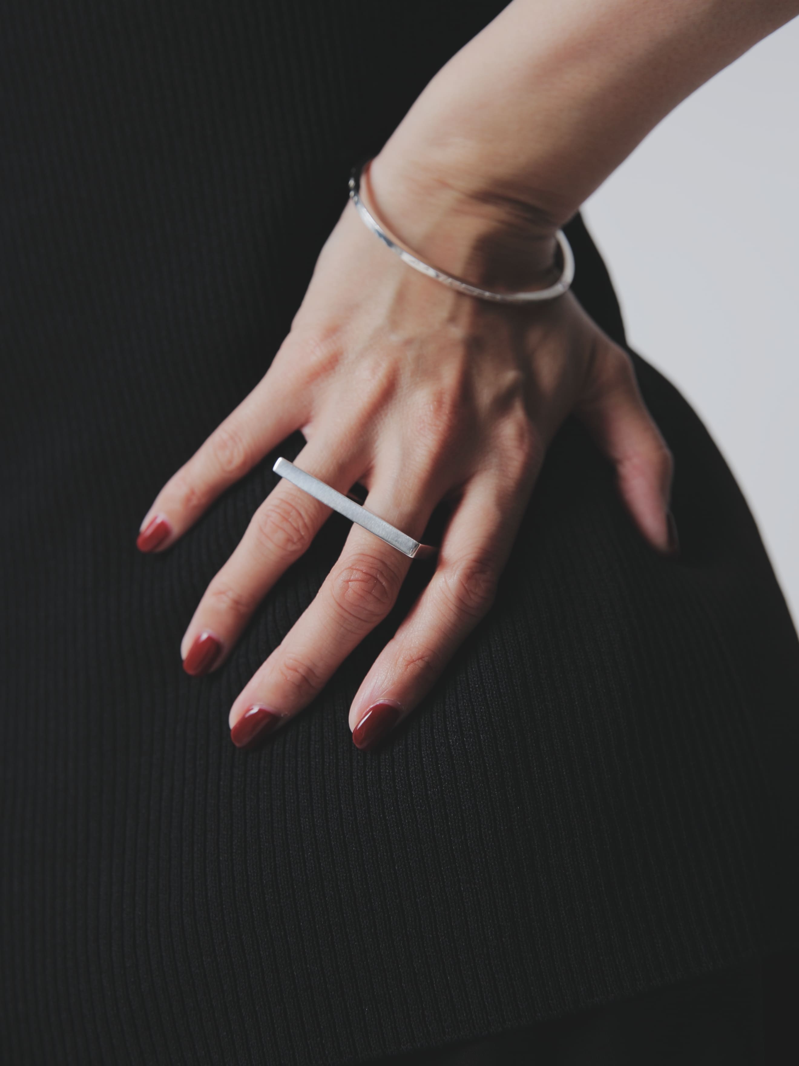 シルバー925製のバングルとバーリングを組み合わせたスタイル。指先まで美しく整えられたネイルとミニマルな装いが印象的。