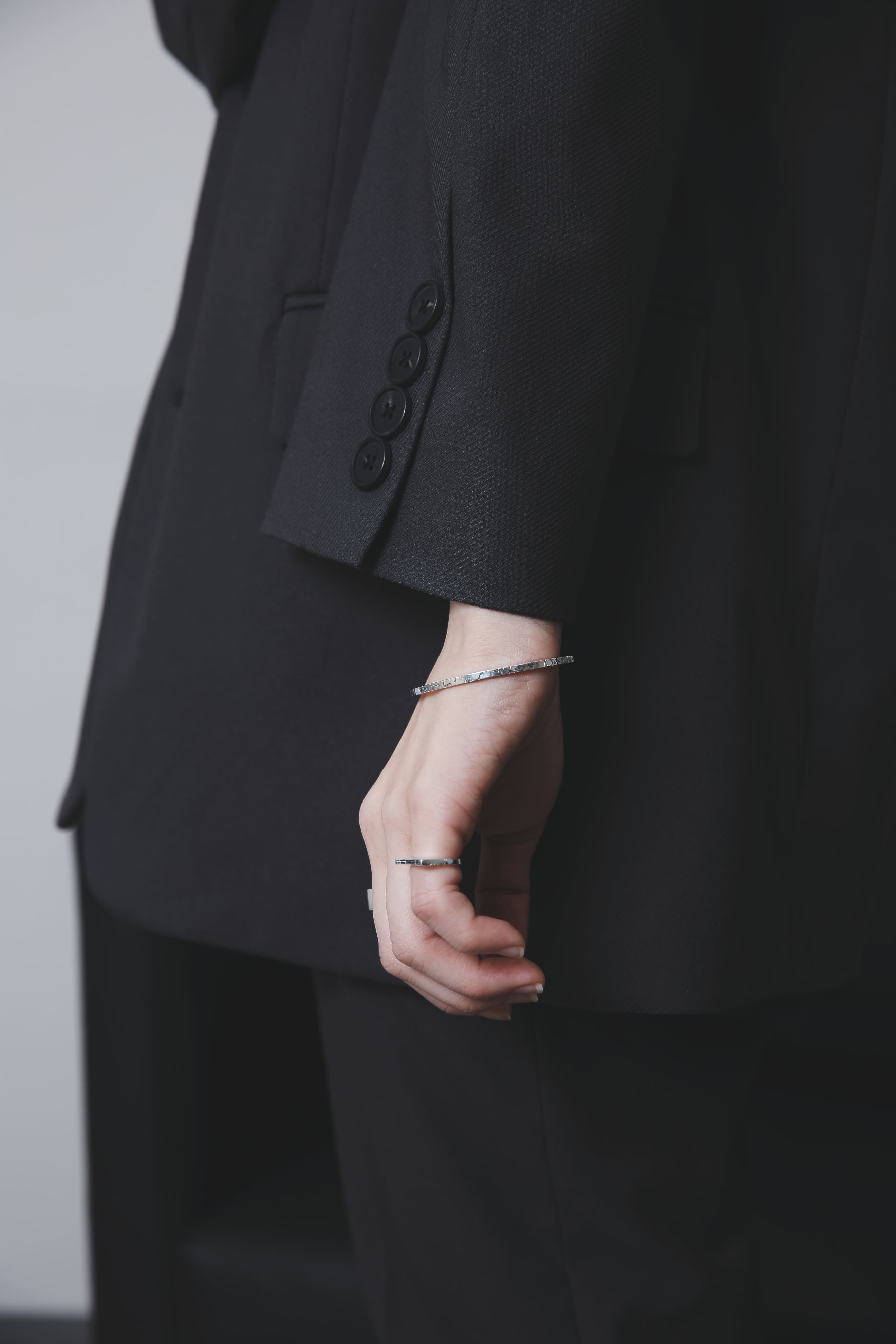 手元を引き締めるシルバー925バングルの着用クローズアップ(ブラックジャケット)