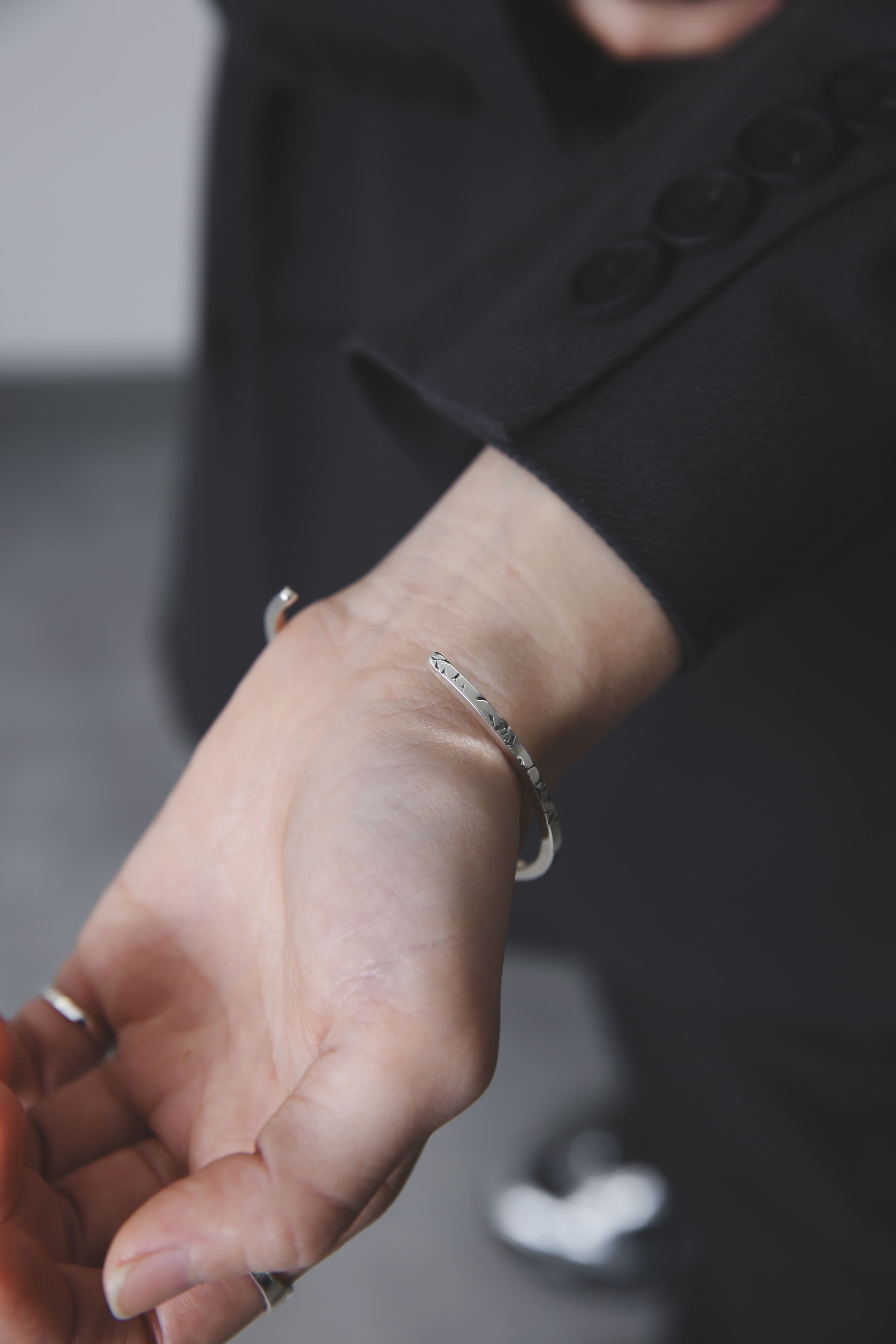 手首に沿うシルバー925バングルのディテールクローズアップ(ブラックスーツコーデ)