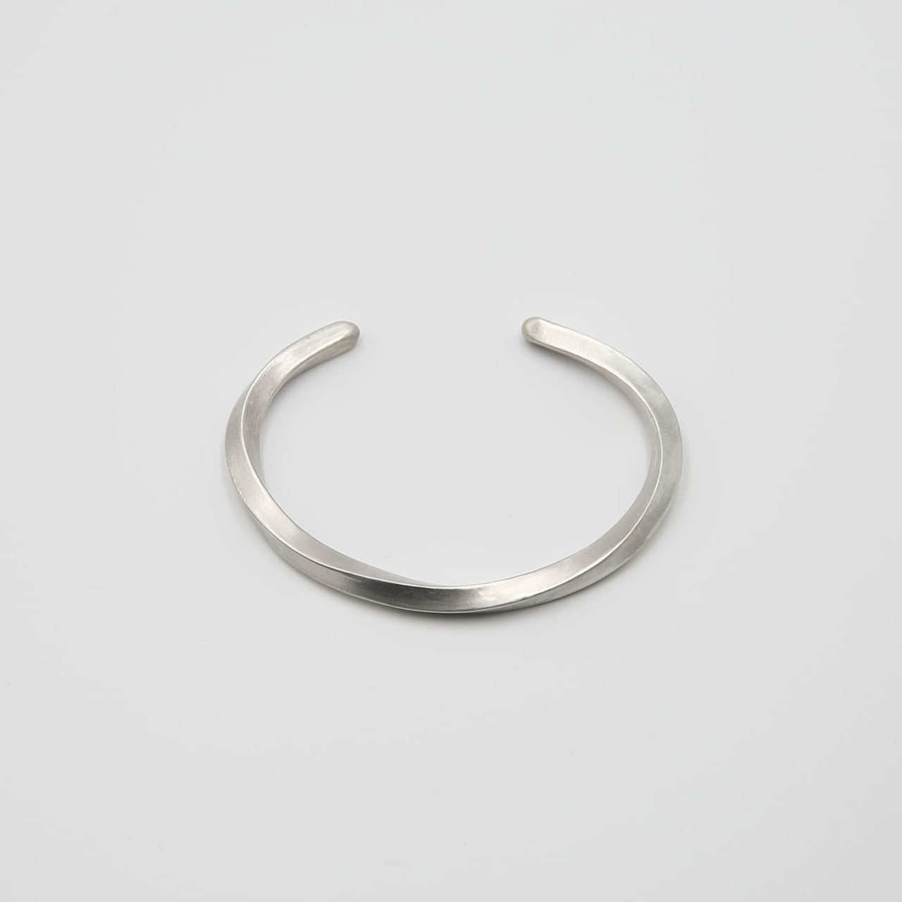 シルバー925製のシンプルなバングル。流れるような曲線が特徴のデザインで、マットな質感が落ち着いた印象を与える。