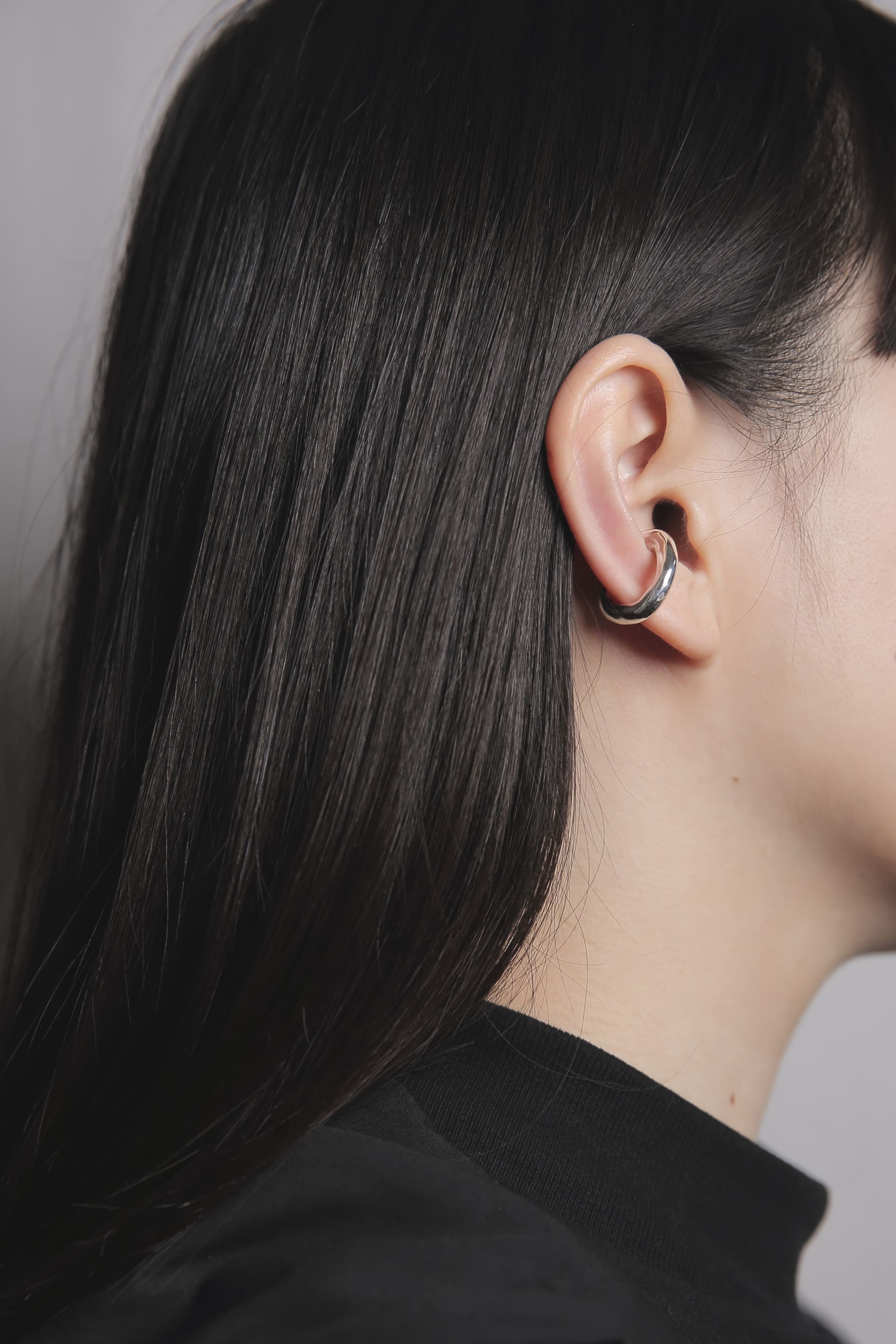 耳の軟骨部分に装着したシルバー925のイヤーカフ。肌馴染みの良い曲線的なフォルムが、顔まわりにモダンで洗練された印象を与えます。