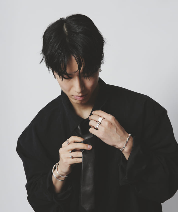 黒い服を着た人物が、両手にシルバー925のリング、ブレスレット、バングルを着用したジュエリースタイリング