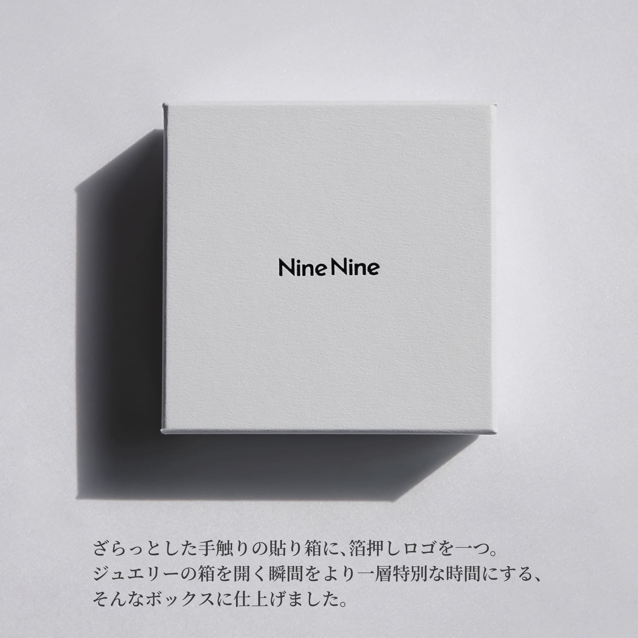 Nine Nineのロゴが中央に箔押しされた、さらりとした質感のホワイトボックス。やわらかな光と影が落ちるミニマルなパッケージイメージ。