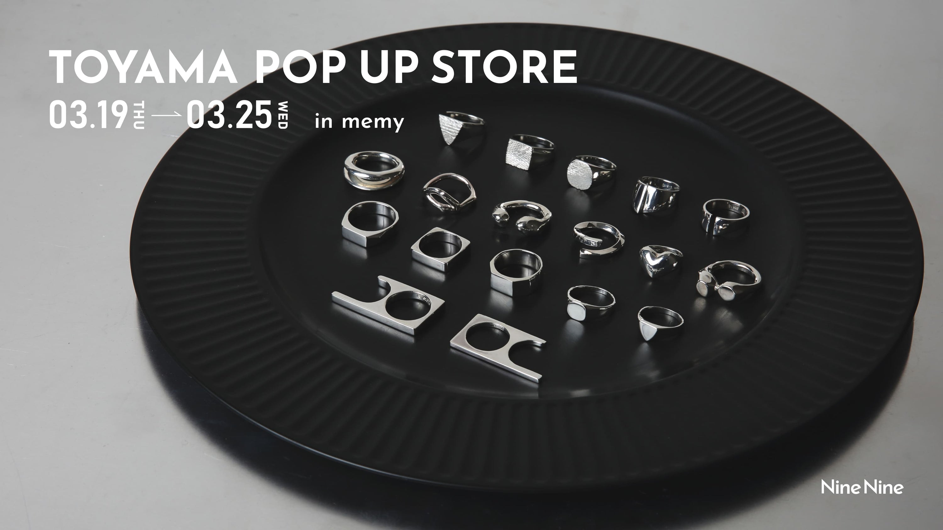 ブラックの大皿に並べられたシルバーリングのコレクションを写したビジュアル。「TOYAMA POP UP STORE 03.19 THU — 03.25 WED in memy」のテキスト入り告知画像。Nine Nineのポップアップストア案内。