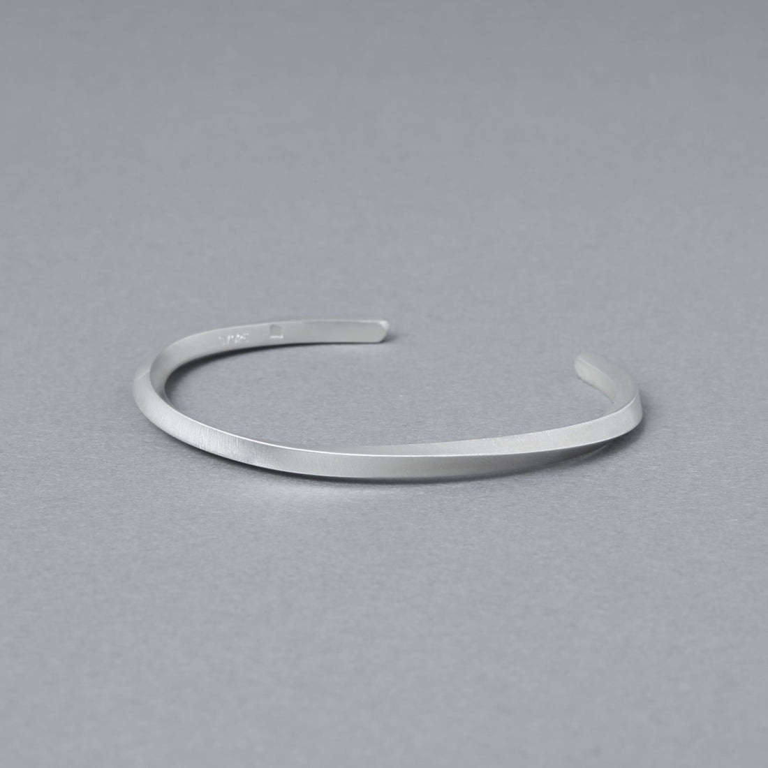 内側の刻印が見える角度で撮影したマットシルバーのバングル。程よい厚みと均一なラインを確認できる商品カット。