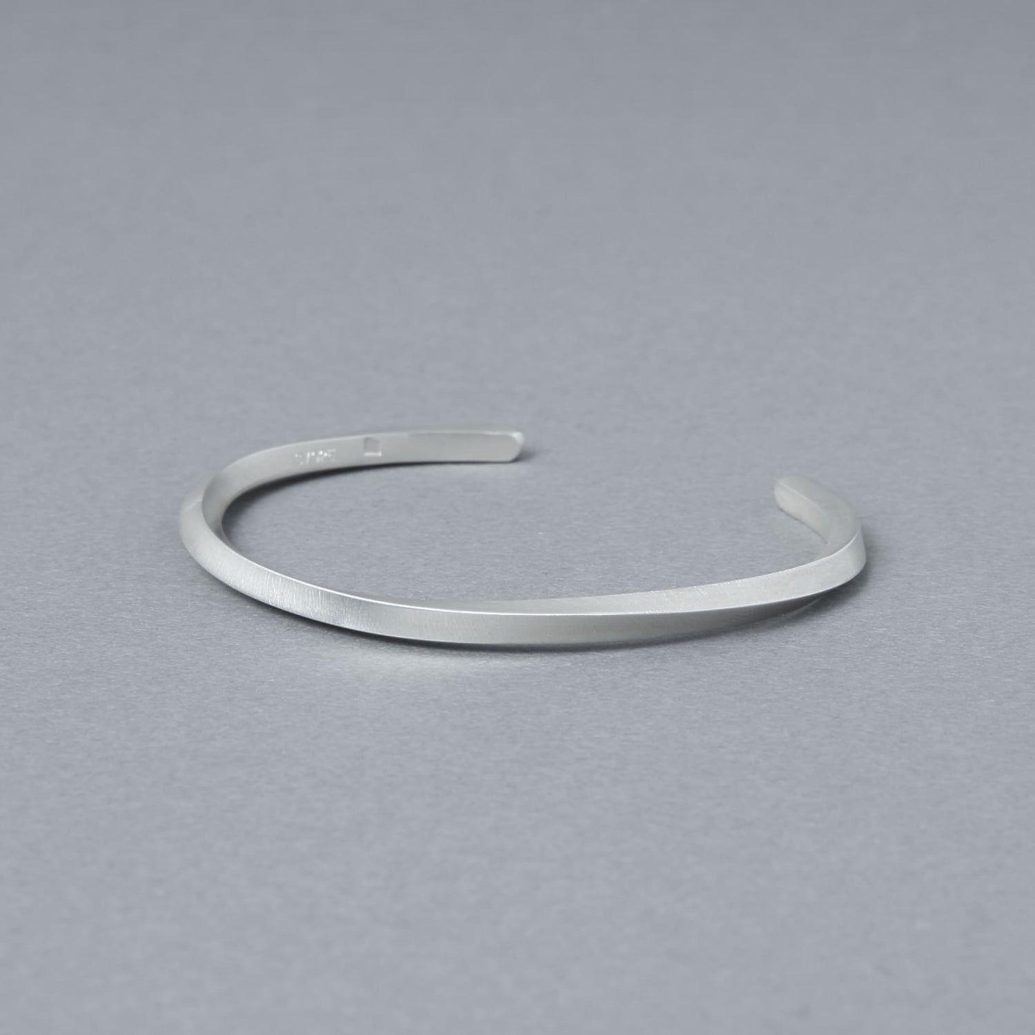 内側の刻印が見える角度で撮影したマットシルバーのバングル。程よい厚みと均一なラインを確認できる商品カット。