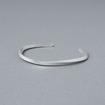 内側の刻印が見える角度で撮影したマットシルバーのバングル。程よい厚みと均一なラインを確認できる商品カット。
