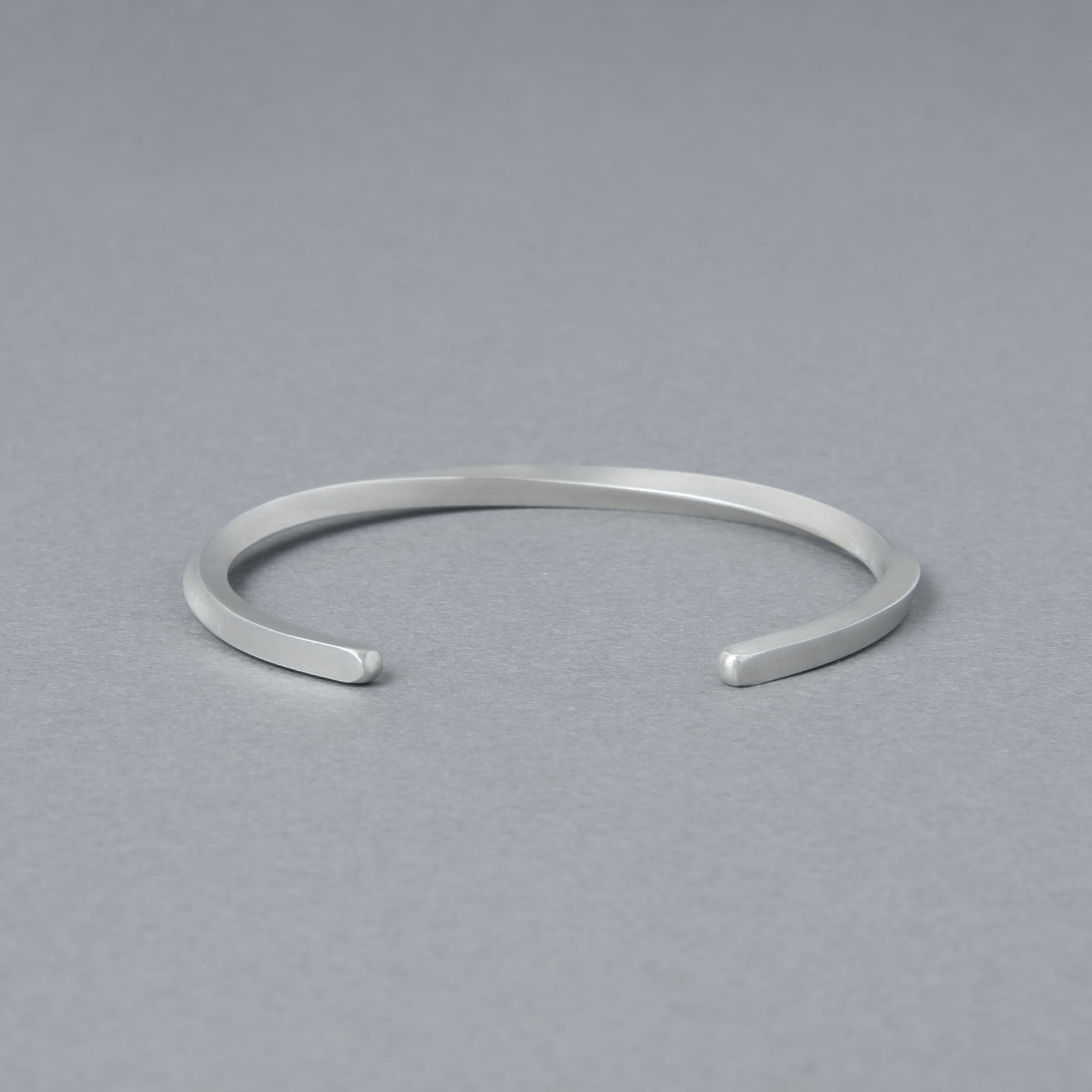 開口部が正面に見える構図のシルバーバングル。シンプルな丸みと均整の取れたフォルムを強調した商品イメージ。