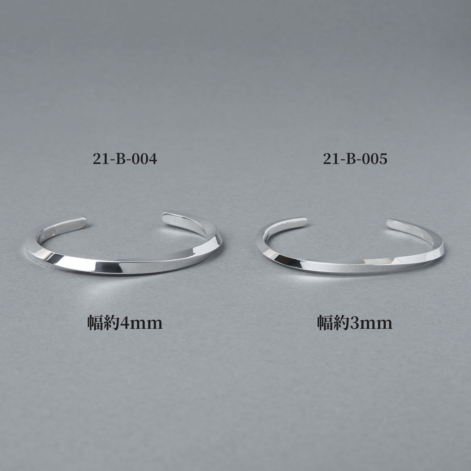 品番21-B-004（幅約4mm）と21-B-005（幅約3mm）のシルバーバングルを並べた比較画像。プレーンでフラットなフォルムの幅違いデザインをグレー背景で撮影した商品イメージ。
