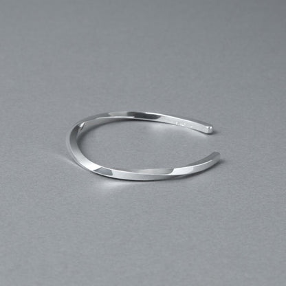 シルバー925バングル「21-B-005」（幅3mm）を、開口部を右側に向けてグレー背景で斜め上から撮影。ねじりのあるフォルムと鏡面仕上げ、内側の刻印が見える商品写真。周囲に余白を残した構図。
