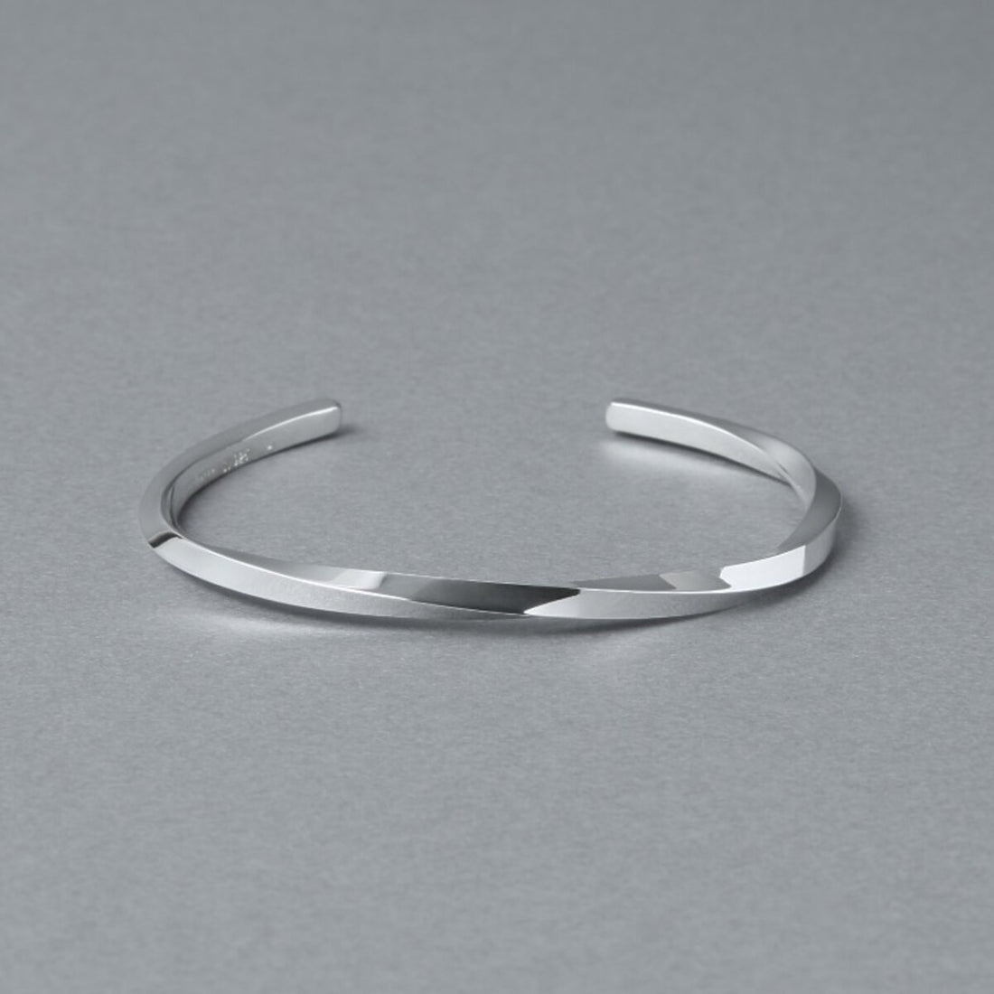シルバー925バングル「21-B-005」（幅3mm）の商品写真。ねじりのあるフォルムと鏡面仕上げの輝き、開口部をグレー背景で斜め上から撮影。