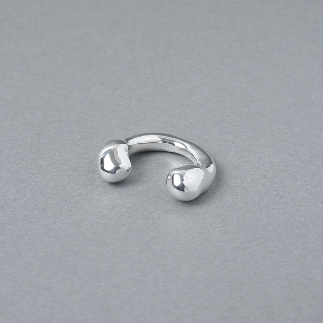 やや角度を変えて置かれたシルバー925のイヤーカフ。重厚感のある艶やかな鏡面仕上げが、シンプルながらも洗練された手作りのような温かみを感じさせます。