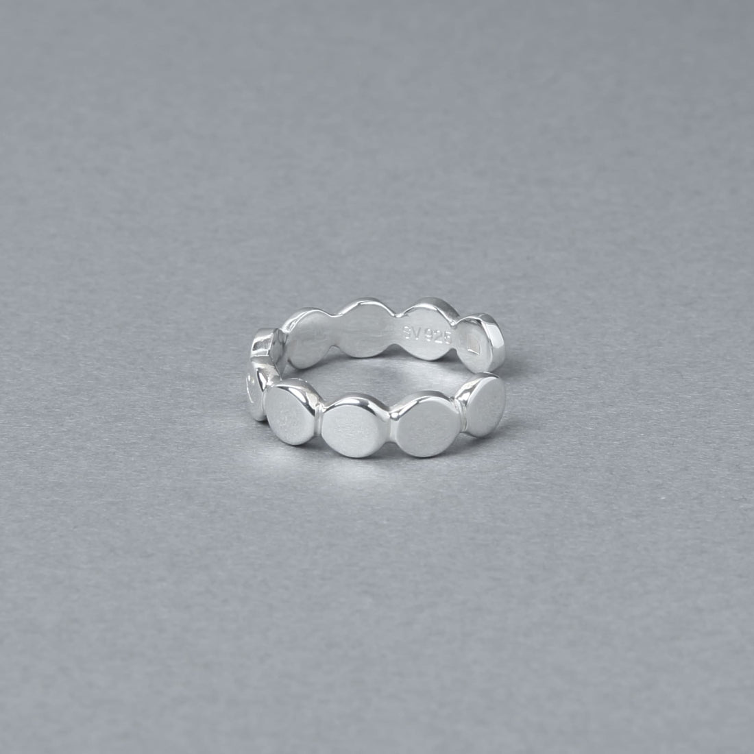 鏡面仕上げのシルバー925素材で作られたサークルモチーフの連なりリング。一つだけスマイルの刻印が施された遊び心のあるデザイン。