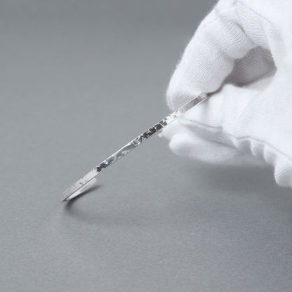 手袋を着用した手で持ったシルバー925細身バングルの質感クローズアップ写真