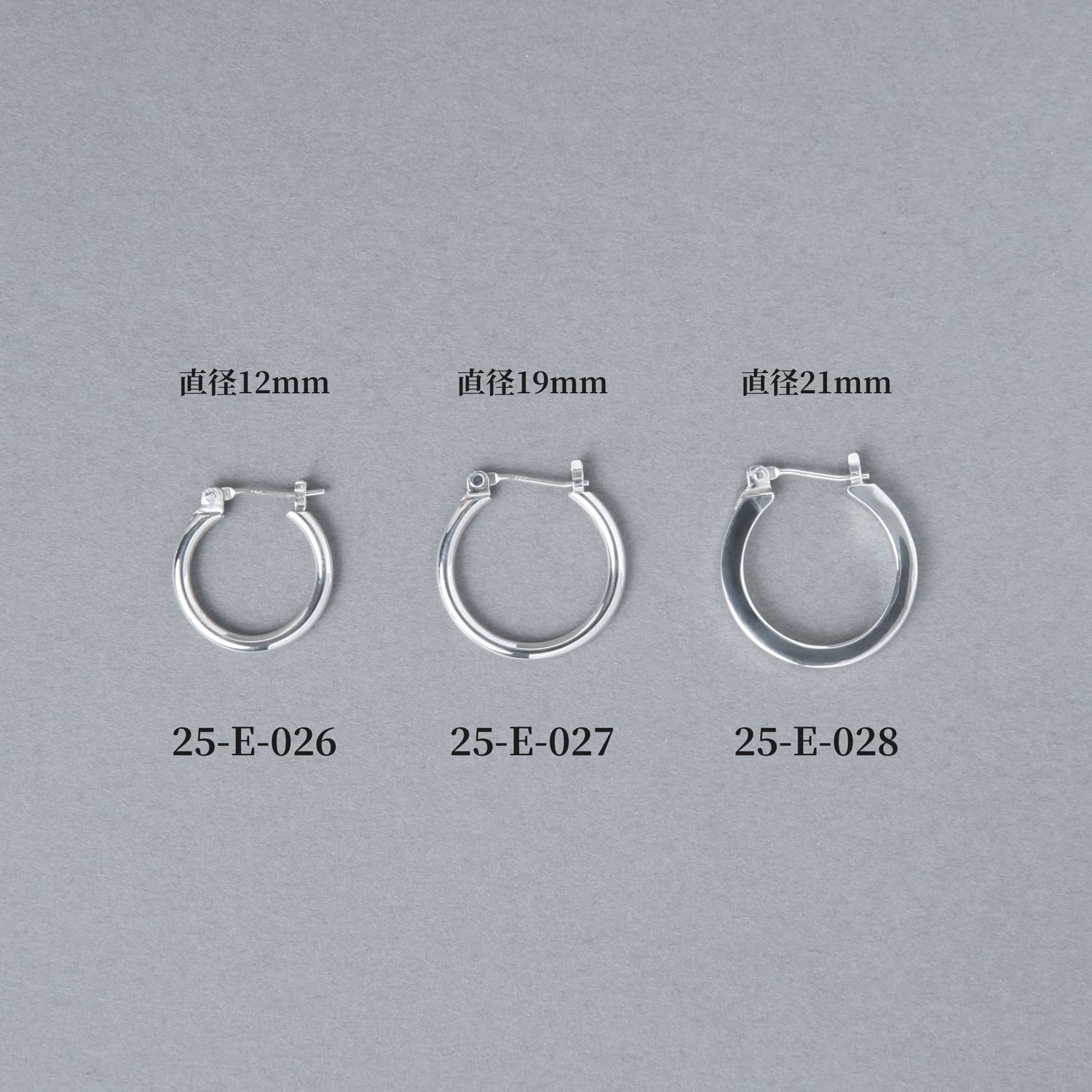 グレー背景に並べられた3サイズのフープピアス。左から直径12mmの25-E-026、19mmの25-E-027、21mmの25-E-028と商品番号とサイズが表示されている比較画像。