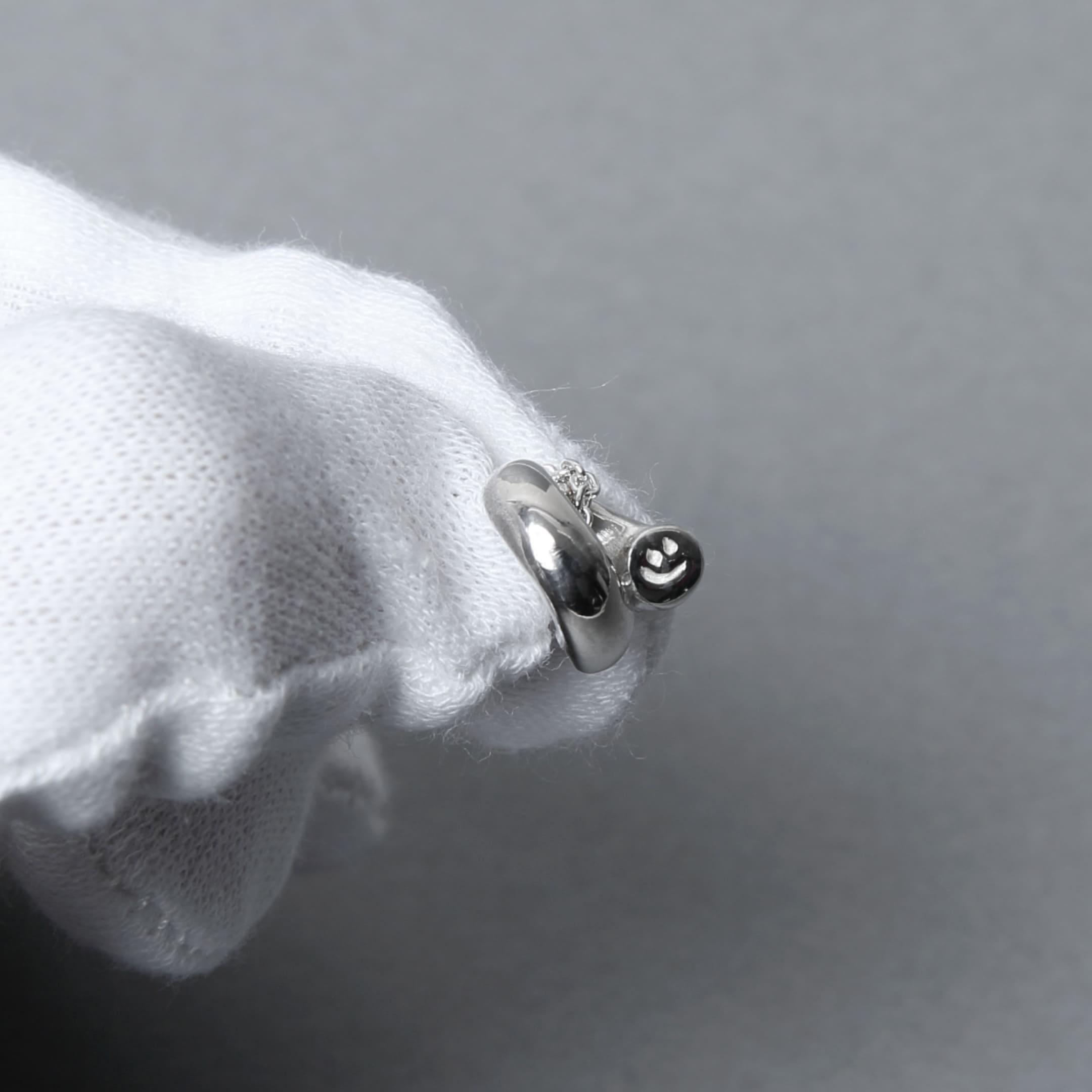 白手袋の上で撮影されたシルバー925のペンダントネックレス。丸みのあるモチーフが艶やかに光を映し出す繊細な造形。