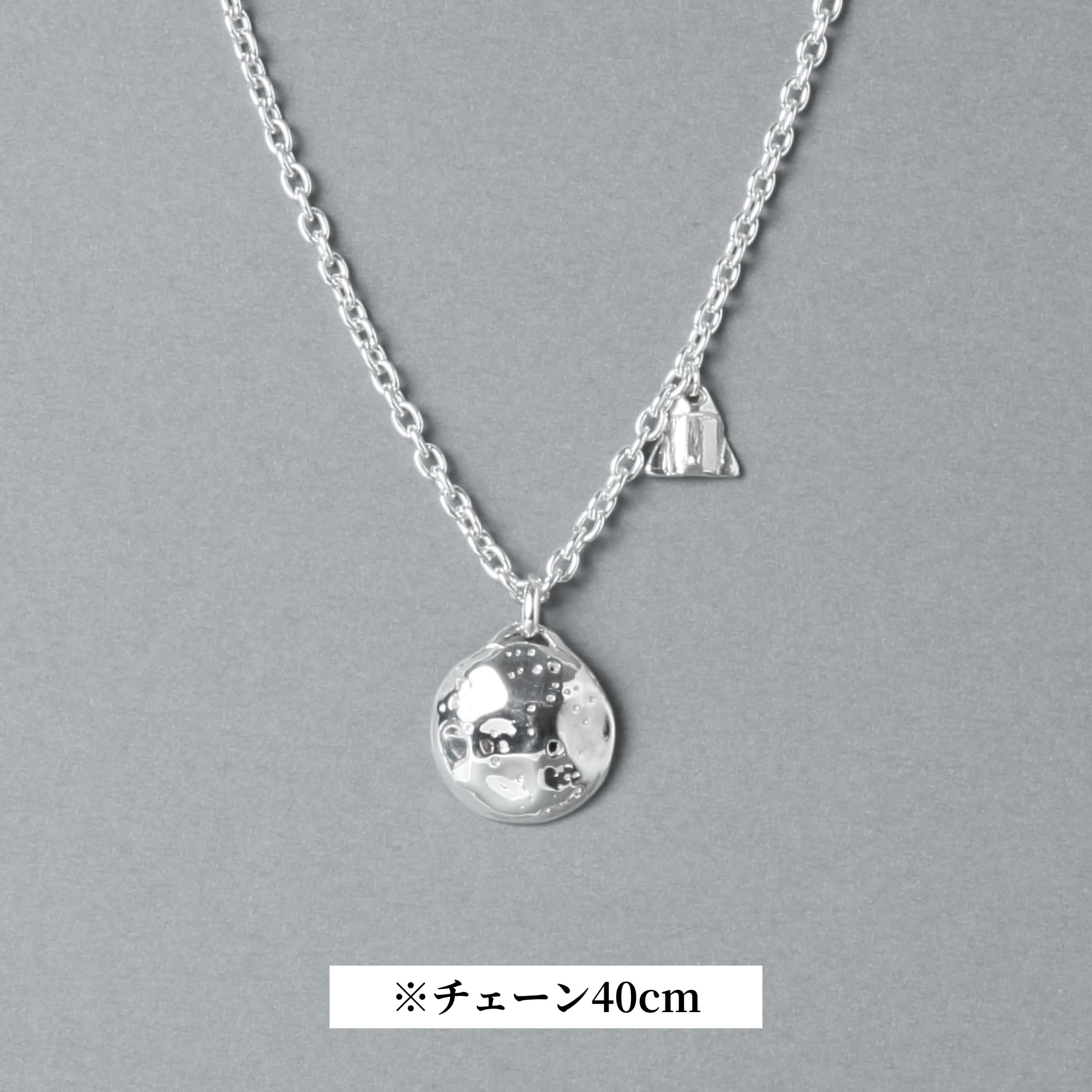 シルバー925製のネックレス。表面にクレーターのような凹凸を施した満月モチーフのトップと、小さなロケットのチャームが並ぶデザイン。