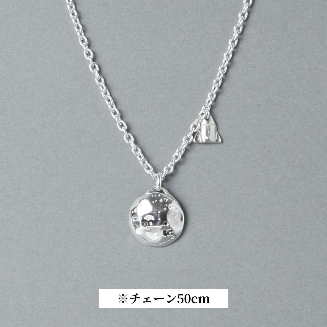 シルバー925製のネックレス。表面にクレーターのような凹凸を施した満月モチーフのトップと、小さなロケットのチャームが並ぶデザイン。