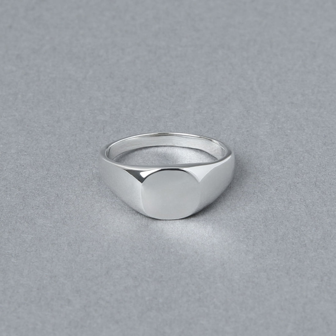 丸みを帯びたトップが特徴のシルバー925製シグネットリング。正面から撮影され、シンプルな鏡面仕上げの美しさが際立つ。