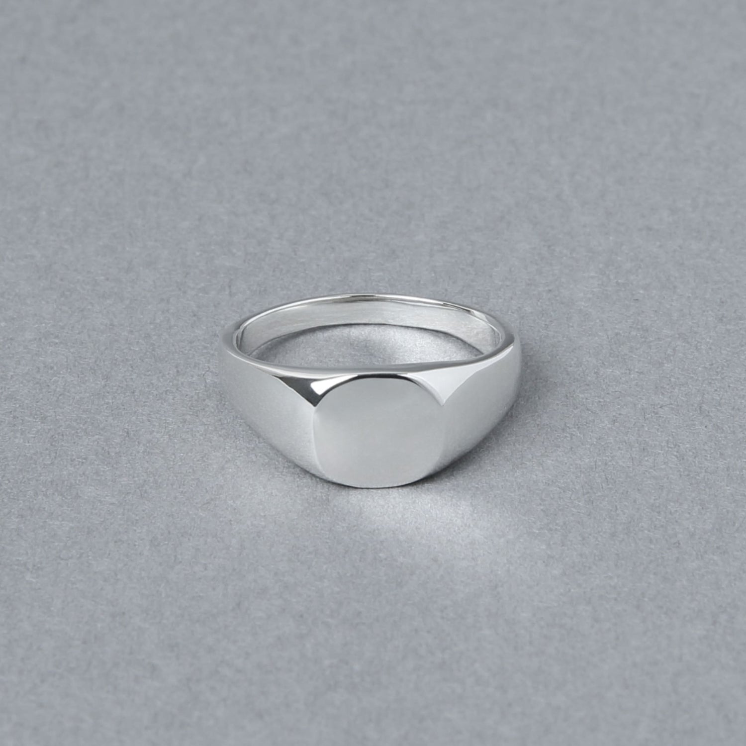 丸みを帯びたトップが特徴のシルバー925製シグネットリング。正面から撮影され、シンプルな鏡面仕上げの美しさが際立つ。