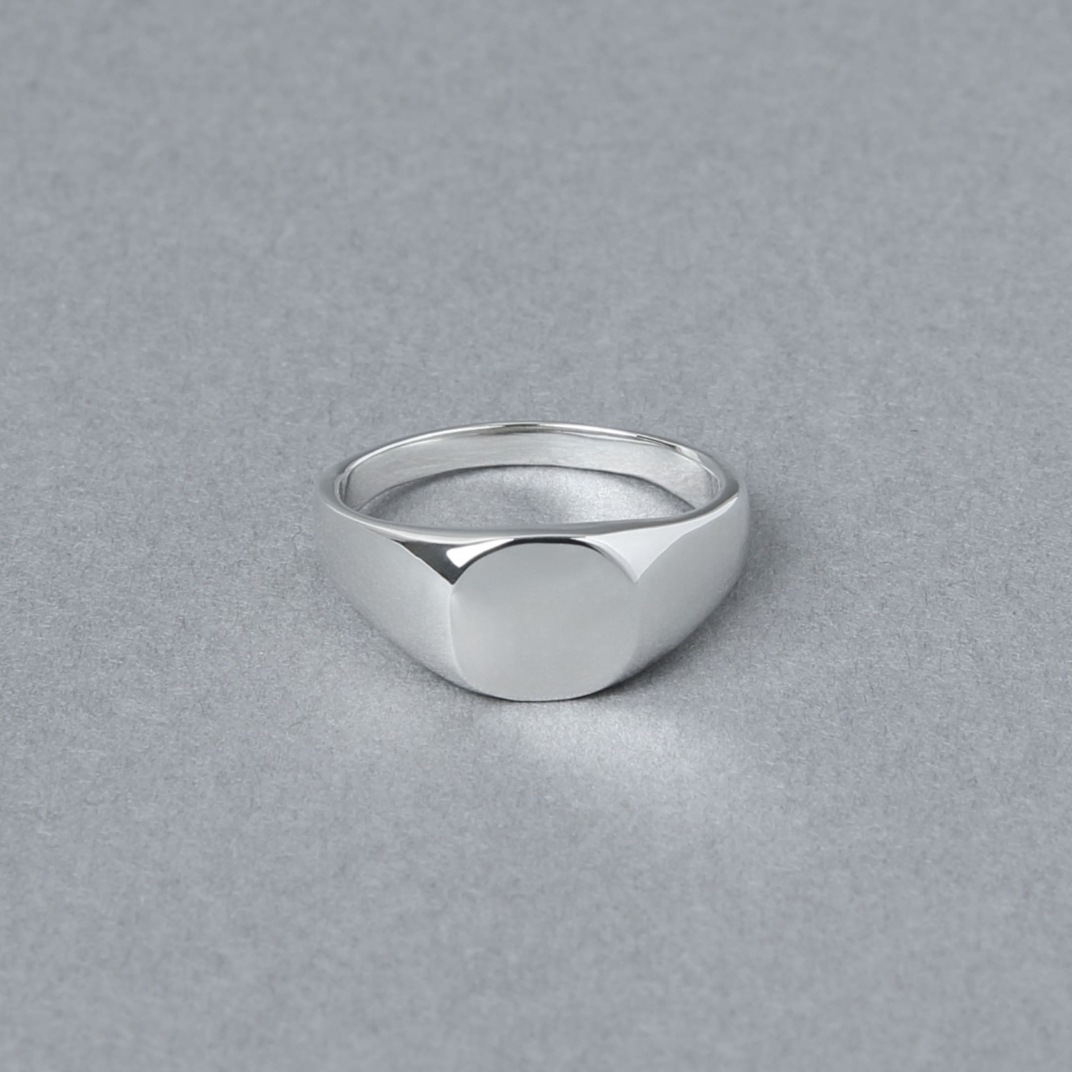 丸みを帯びたトップが特徴のシルバー925製シグネットリング。正面から撮影され、シンプルな鏡面仕上げの美しさが際立つ。