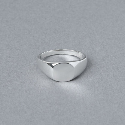 丸みを帯びたトップが特徴のシルバー925製シグネットリング。正面から撮影され、シンプルな鏡面仕上げの美しさが際立つ。