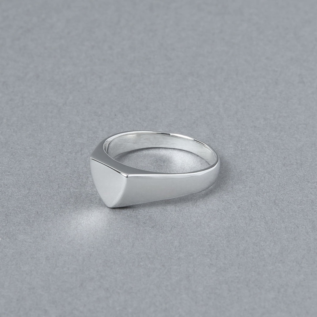 シャープな三角フォルムをもつシグネットリングを斜めから撮影。滑らかな鏡面仕上げが、ピンキーリングとしても映える洗練された印象を与える。