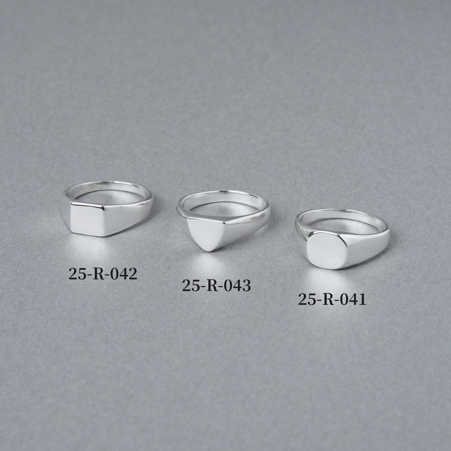 スクエア、トライアングル、ラウンドの3種類のシグネットリングを並べた比較画像。左端に「25-R-042」としてラウンド型リングが配置されている。