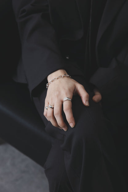 膝の上に手を置いたスタイルカット。シルバー925のリングとチェーンブレスレットが上品な存在感を放ち、静かな強さを感じさせる。