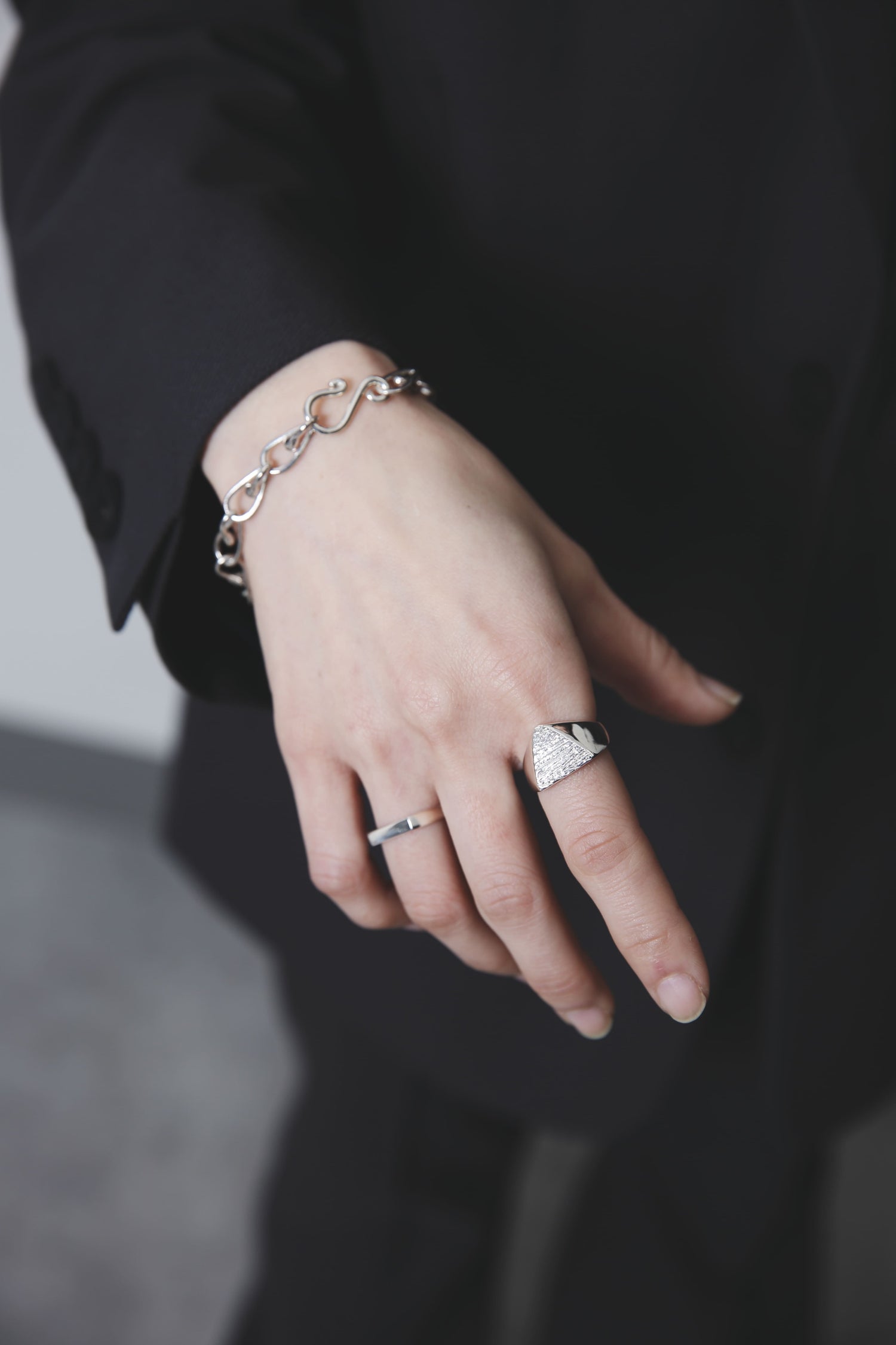 リングをつけた手元を見せるカット。木目模様の三角シルバーリングが指先に力強さを添え、洗練された印象を演出している。