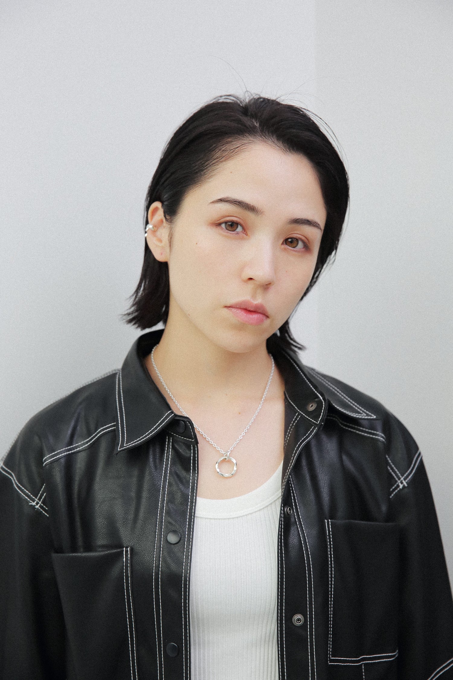 女性の耳に馴染むサイズのシルバー925製イヤーカフ。光を反射する鏡面仕上げの質感が、黒髪やレザーの質感とコントラストを生み、ジュエリーの存在感を際立たせます。