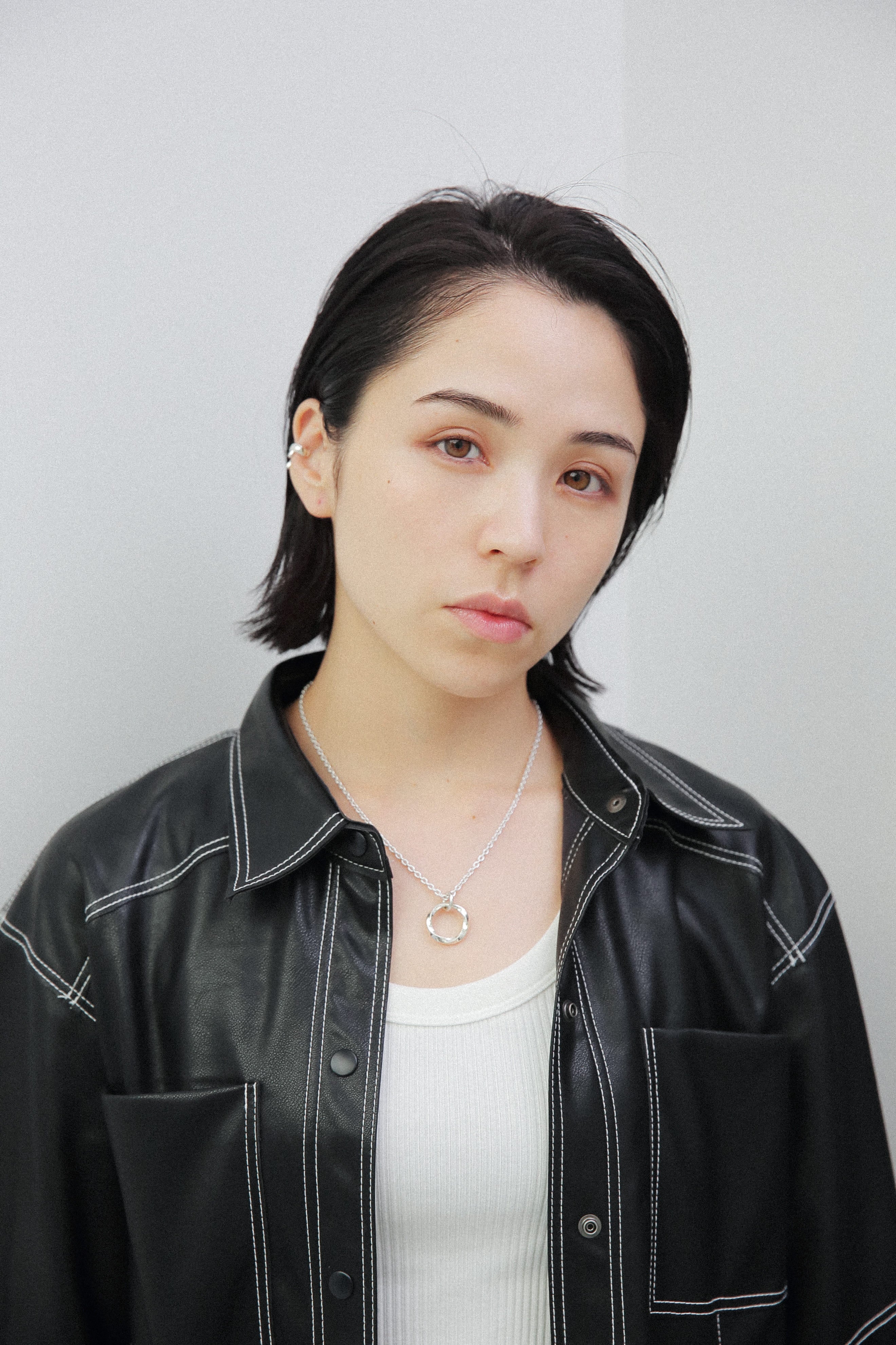 女性の耳に馴染むサイズのシルバー925製イヤーカフ。光を反射する鏡面仕上げの質感が、黒髪やレザーの質感とコントラストを生み、ジュエリーの存在感を際立たせます。