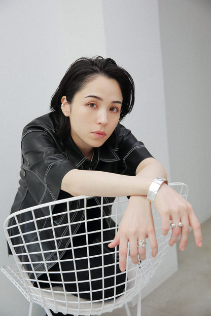 女性の耳に馴染むサイズのシルバー925製イヤーカフ。光を反射する鏡面仕上げの質感が、黒髪やレザーの質感とコントラストを生み、ジュエリーの存在感を際立たせます。