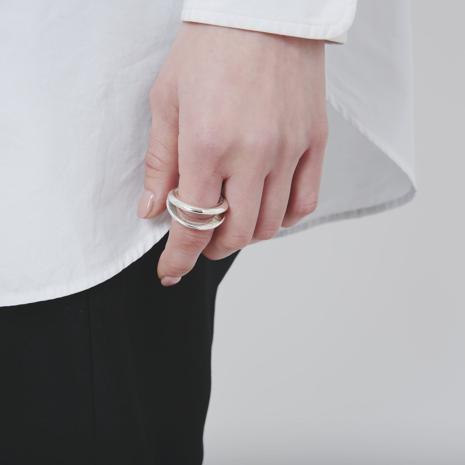腰元に置いた手元を捉えた、シルバー925リングの着用詳細。重なり合うラインが特徴的