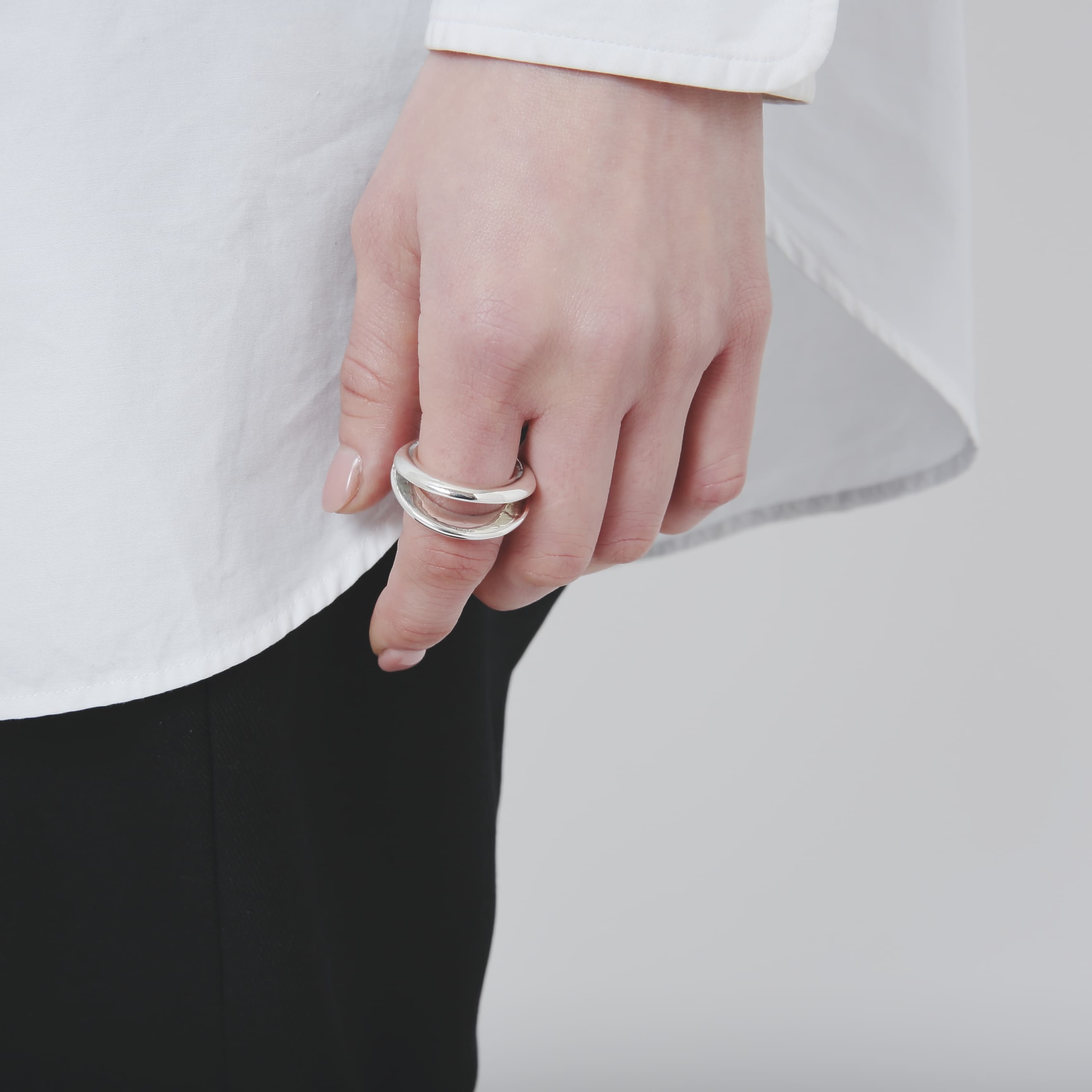 腰元に置いた手元を捉えた、シルバー925リングの着用詳細。重なり合うラインが特徴的